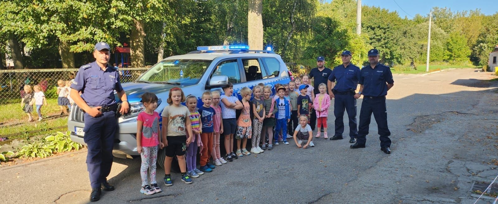 Dnia 28.09.2023r.nasze przedszkolaki miały okazję spotkać się z policjantami. Podczas spotkania przedszkolaki przypomniały sobie zasady bezpiecznego poruszania się po drogach, jak reagować w sytuacjach różnych zagrożeń. Goście ostrzegali też przed osobami nieznajomymi z którymi nie wolno rozmawiać oraz wpuszczać ich do domu. Dzieci wysłuchały policyjnych rad oraz zadawały wiele interesujących pytań. Szczególnym zainteresowaniem wśród dzieci cieszyła się prezentacja wyposażenia policyjnego, niezbędnego podczas wykonywania pracy. Mieliśmy ponadto możliwość obejrzenia krótkich filmików w przedszkolu jak bezpiecznie przejść przez jezdnię oraz jakie numery alarmowe powinien znać każdy, aby wezwać pomocy w razie potrzeby.
Dzieci chętnie wysłuchały opowiadań o codziennej pracy policjanta. Spotkanie przebiegało w bardzo miłej atmosferze. Na zakończenie pan policjant wręczył wszystkim dzieciom sześcioletnim odblaski. 
Serdecznie dziękujemy za miłe spotkanie, to spotkanie oraz treści przekazane na pewno na długo pozostaną w naszej pamięci.