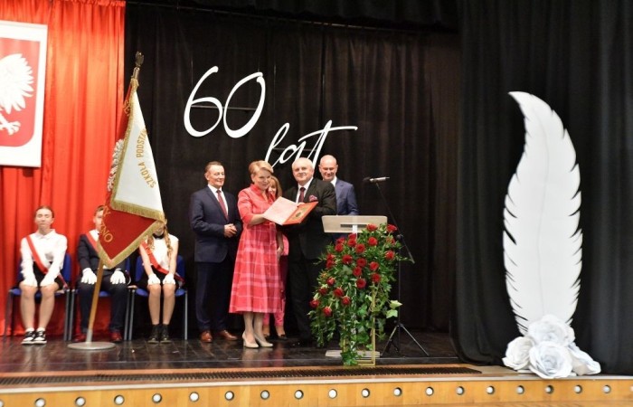 20 października świętowaliśmy Jubileusz 60-lecia Szkoły Podstawowej nr 2 w Pasłęku. Był to dla nas szczególny dzień, czas, w którym w symboliczny sposób przenieśliśmy się do chwili powstania naszej szkoły. Cieszymy się bardzo, że tak ważne dla nas wydarzenie swą obecnością uświetnili: minister Andrzej Śliwka - podsekretarz stanu w Ministerstwie Aktywów Państwowych, Burmistrz Pasłęka Pan Wiesław Śniecikowski, Przewodniczący Rady Miejskiej w Pasłęku Pan Marian Matuszczak, Starosta Powiatu Elbląskiego Pan Maciej Romanowski, wiceburmistrz Pan Marek Sarnowski, dyrektorzy i przedstawiciele instytucji oświatowych, służb mundurowych, działacze stowarzyszeń i związków zawodowych, emeryci oraz liczni absolwenci Szkoły Podstawowej nr 2 w Pasłęku.
Obchody jubileuszu rozpoczęliśmy od posadzenia drzewka przed pomnikiem patrona, Władysława Broniewskiego i przecięcia wstęgi na ławeczce upamiętniającej tę wyjątkową rocznicę. Następnie, już w auli, głos zabrała Pani Dyrektor Agnieszka Cieklińska, dzięki której wspomnienia związane z historią szkoły na nowo odżyły w pamięci zebranych. W pięknych słowach usłyszeliśmy o początkach szkoły, przypomnieliśmy sobie losy ludzi z nią związanych, ich sukcesy i zmagania, dzięki którym my dzisiaj możemy być częścią wyjątkowego miejsca, tak mocno wpisującego się w historię naszego miasta.