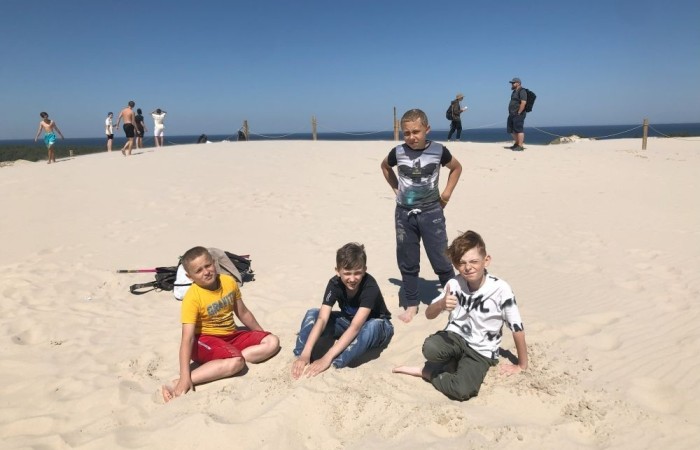 W dniach 15-18 maja 2024 roku uczniowie klas 4A i 5B wybrali się na wycieczkę do Łeby. Oto krótkie podsumowanie ich przygody.
Wizyta w Słowińskim Parku Narodowym była niezapomniana. Ruchome wydmy to unikalne miejsce, gdzie piaskowe pagórki przemieszczają się pod wpływem wiatru. Uczniowie mieli okazję spacerować po tych wydmach i podziwiać piękno natury.
W Łebie Parku czekało na nich wiele atrakcji: Zamek Strachu - dla odważnych, którzy lubią emocje; pojazdy Flinstonów - ciekawa atrakcja dla fanów kultowego serialu, Kopalnia złota - poszukiwanie skarbów; Labirynt magicznych luster - złudzenie nieskończonego lustra; zjeżdżalnie wodne 4 w 1 oraz zjeżdżalnia Boomerang - dla fanów wodnych atrakcji, zjazd na pontonach bez potrzeby przebierania się w stroje kąpielowe, wysokość ślizgu – 10 metrów; Diabelski Młyn, wysoki na 27 metrów wyposażony w 20 gondoli stoi nieopodal naszych zjeżdżalni, widok z góry zapiera dech w piersiach; park trampolin - ogromna przestrzeń, wypełniona parkourem, trampolinami, koszykówką, a także miejscem do robienia salt,  po których bezpiecznie wylądujesz na poduchę; autodrom - atrakcja którą zna niemal każdy! To must-have każdego parku rozrywki.
Uczniowie przemieszczali się po Łebie na melexach, co było wygodnym i ekscytującym środkiem transportu. Na koniec dnia uczniowie odpoczywali w Ośrodku Wypoczynkowym Fregata, gdzie mogli zrelaksować się po pełnym wrażeń dniu.
Wycieczka była udana, a uczniowie wrócili do domu z pięknymi wspomnieniami!