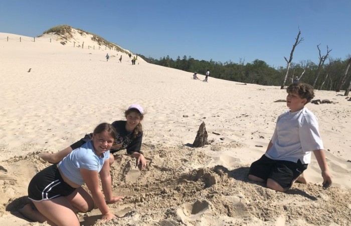 W dniach 15-18 maja 2024 roku uczniowie klas 4A i 5B wybrali się na wycieczkę do Łeby. Oto krótkie podsumowanie ich przygody.
Wizyta w Słowińskim Parku Narodowym była niezapomniana. Ruchome wydmy to unikalne miejsce, gdzie piaskowe pagórki przemieszczają się pod wpływem wiatru. Uczniowie mieli okazję spacerować po tych wydmach i podziwiać piękno natury.
W Łebie Parku czekało na nich wiele atrakcji: Zamek Strachu - dla odważnych, którzy lubią emocje; pojazdy Flinstonów - ciekawa atrakcja dla fanów kultowego serialu, Kopalnia złota - poszukiwanie skarbów; Labirynt magicznych luster - złudzenie nieskończonego lustra; zjeżdżalnie wodne 4 w 1 oraz zjeżdżalnia Boomerang - dla fanów wodnych atrakcji, zjazd na pontonach bez potrzeby przebierania się w stroje kąpielowe, wysokość ślizgu – 10 metrów; Diabelski Młyn, wysoki na 27 metrów wyposażony w 20 gondoli stoi nieopodal naszych zjeżdżalni, widok z góry zapiera dech w piersiach; park trampolin - ogromna przestrzeń, wypełniona parkourem, trampolinami, koszykówką, a także miejscem do robienia salt,  po których bezpiecznie wylądujesz na poduchę; autodrom - atrakcja którą zna niemal każdy! To must-have każdego parku rozrywki.
Uczniowie przemieszczali się po Łebie na melexach, co było wygodnym i ekscytującym środkiem transportu. Na koniec dnia uczniowie odpoczywali w Ośrodku Wypoczynkowym Fregata, gdzie mogli zrelaksować się po pełnym wrażeń dniu.
Wycieczka była udana, a uczniowie wrócili do domu z pięknymi wspomnieniami!