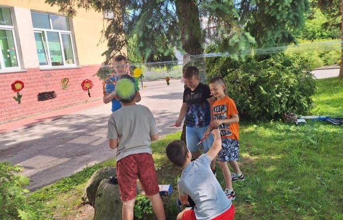 W ostatnim czasie uczniowie klasy III b wzięli udział w wyjątkowych zajęciach plastycznych, które wprawiły ich w zachwyt i radość tworzenia. Tym razem nasze artystyczne dusze miały okazję malować na świeżym powietrzu. Wyjątkowy pomysł na wykorzystanie folii spożywczej rozciągniętej pomiędzy drzewami okazał się strzałem w dziesiątkę. Uczniowie mogli wyrażać swoją kreatywność, eksperymentować z kolorami i formami, czerpiąc inspirację z natury otaczającej naszą szkołę.