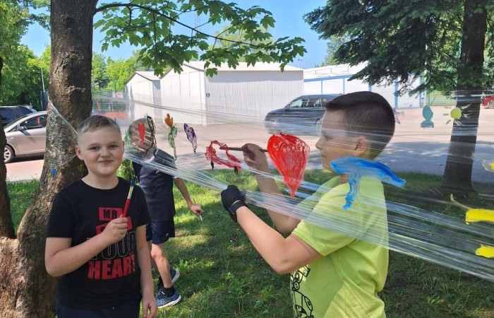 W ostatnim czasie uczniowie klasy III b wzięli udział w wyjątkowych zajęciach plastycznych, które wprawiły ich w zachwyt i radość tworzenia. Tym razem nasze artystyczne dusze miały okazję malować na świeżym powietrzu. Wyjątkowy pomysł na wykorzystanie folii spożywczej rozciągniętej pomiędzy drzewami okazał się strzałem w dziesiątkę. Uczniowie mogli wyrażać swoją kreatywność, eksperymentować z kolorami i formami, czerpiąc inspirację z natury otaczającej naszą szkołę.