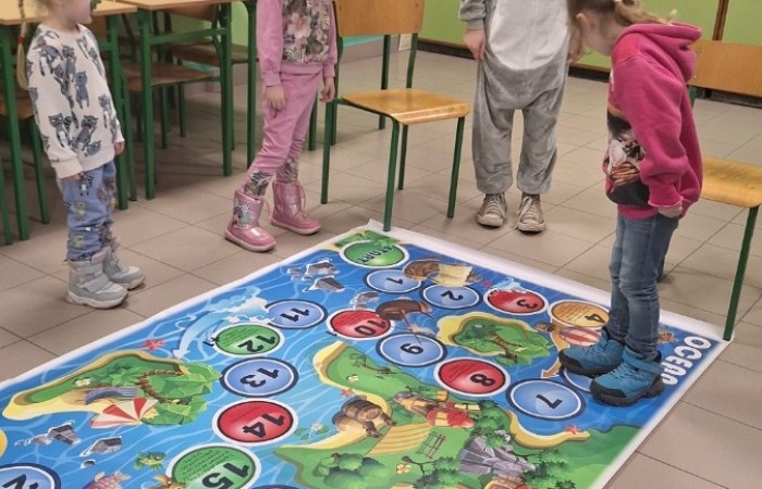 26 lutego w naszej szkole odbył się wyjątkowy DZIEŃ OTWARTY, podczas którego mieliśmy przyjemność gościć przedszkolaków, przyszłych uczniów oraz ich rodziców. Była to doskonała okazja, aby poczuć atmosferę naszej szkoły, poznać jej ofertę edukacyjną i odkryć to, co czyni ją miejscem pełnym pasji, wiedzy i radości.
Zwiedzanie naszej placówki obejmowało sale przedmiotowe, bibliotekę, stołówkę, świetlicę oraz małą salę gimnastyczną, gdzie można było na własnej skórze poczuć rytm codziennego życia naszej szkolnej społeczności.
Na odwiedzających czekało mnóstwo niespodzianek! Zachętą do działania były pieczątki, które najmłodsi otrzymywali w nagrodę za wykonanie przeróżnych zadań. W sali gimnastycznej na uczestników czekały ekscytujące konkurencje sprawnościowe, a w pracowni kulinarnej – pachnące i chrupiące gofry własnej roboty. Młodzi odkrywcy mieli okazję badać świat przez mikroskop, eksperymentować z interaktywnymi robotami Photon oraz brać udział w zajęciach z robotyki. Z kolei miłośnicy sztuki mogli tworzyć piękne dzieła na warsztatach plastycznych i origami, a najmłodsi cieszyli się malowaniem twarzy.
Nie zabrakło także wyzwań dla bystrego umysłu! Gry i zabawy językowe, rebusy oraz polonistyczne łamigłówki rozbudzały wyobraźnię i rozwijały umiejętności językowe. Wesoła „Gimnastyka buzi i języka” sprawiła, że ćwiczenie dykcji stało się czystą przyjemnością. Ogromnym zainteresowaniem cieszyły się również gry planszowe, które dostarczyły mnóstwa radości i emocjonującej rywalizacji. Dodatkowo, zabawy z chustą Klanza okazały się świetnym sposobem na integrację i wspólną zabawę pełną śmiechu.
Aktywne zwiedzanie stało się więc okazją do rozwijania ciekawości świata, nabywania nowych umiejętności, pobudzania w najmłodszych kreatywności oraz odczuwania satysfakcji z osiągniętego sukcesu.