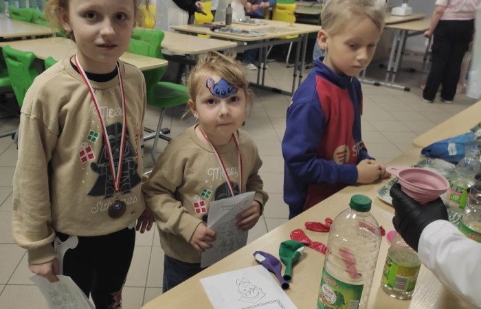 26 lutego w naszej szkole odbył się wyjątkowy DZIEŃ OTWARTY, podczas którego mieliśmy przyjemność gościć przedszkolaków, przyszłych uczniów oraz ich rodziców. Była to doskonała okazja, aby poczuć atmosferę naszej szkoły, poznać jej ofertę edukacyjną i odkryć to, co czyni ją miejscem pełnym pasji, wiedzy i radości.
Zwiedzanie naszej placówki obejmowało sale przedmiotowe, bibliotekę, stołówkę, świetlicę oraz małą salę gimnastyczną, gdzie można było na własnej skórze poczuć rytm codziennego życia naszej szkolnej społeczności.
Na odwiedzających czekało mnóstwo niespodzianek! Zachętą do działania były pieczątki, które najmłodsi otrzymywali w nagrodę za wykonanie przeróżnych zadań. W sali gimnastycznej na uczestników czekały ekscytujące konkurencje sprawnościowe, a w pracowni kulinarnej – pachnące i chrupiące gofry własnej roboty. Młodzi odkrywcy mieli okazję badać świat przez mikroskop, eksperymentować z interaktywnymi robotami Photon oraz brać udział w zajęciach z robotyki. Z kolei miłośnicy sztuki mogli tworzyć piękne dzieła na warsztatach plastycznych i origami, a najmłodsi cieszyli się malowaniem twarzy.
Nie zabrakło także wyzwań dla bystrego umysłu! Gry i zabawy językowe, rebusy oraz polonistyczne łamigłówki rozbudzały wyobraźnię i rozwijały umiejętności językowe. Wesoła „Gimnastyka buzi i języka” sprawiła, że ćwiczenie dykcji stało się czystą przyjemnością. Ogromnym zainteresowaniem cieszyły się również gry planszowe, które dostarczyły mnóstwa radości i emocjonującej rywalizacji. Dodatkowo, zabawy z chustą Klanza okazały się świetnym sposobem na integrację i wspólną zabawę pełną śmiechu.
Aktywne zwiedzanie stało się więc okazją do rozwijania ciekawości świata, nabywania nowych umiejętności, pobudzania w najmłodszych kreatywności oraz odczuwania satysfakcji z osiągniętego sukcesu.