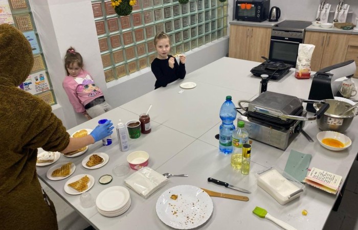 26 lutego w naszej szkole odbył się wyjątkowy DZIEŃ OTWARTY, podczas którego mieliśmy przyjemność gościć przedszkolaków, przyszłych uczniów oraz ich rodziców. Była to doskonała okazja, aby poczuć atmosferę naszej szkoły, poznać jej ofertę edukacyjną i odkryć to, co czyni ją miejscem pełnym pasji, wiedzy i radości.
Zwiedzanie naszej placówki obejmowało sale przedmiotowe, bibliotekę, stołówkę, świetlicę oraz małą salę gimnastyczną, gdzie można było na własnej skórze poczuć rytm codziennego życia naszej szkolnej społeczności.
Na odwiedzających czekało mnóstwo niespodzianek! Zachętą do działania były pieczątki, które najmłodsi otrzymywali w nagrodę za wykonanie przeróżnych zadań. W sali gimnastycznej na uczestników czekały ekscytujące konkurencje sprawnościowe, a w pracowni kulinarnej – pachnące i chrupiące gofry własnej roboty. Młodzi odkrywcy mieli okazję badać świat przez mikroskop, eksperymentować z interaktywnymi robotami Photon oraz brać udział w zajęciach z robotyki. Z kolei miłośnicy sztuki mogli tworzyć piękne dzieła na warsztatach plastycznych i origami, a najmłodsi cieszyli się malowaniem twarzy.
Nie zabrakło także wyzwań dla bystrego umysłu! Gry i zabawy językowe, rebusy oraz polonistyczne łamigłówki rozbudzały wyobraźnię i rozwijały umiejętności językowe. Wesoła „Gimnastyka buzi i języka” sprawiła, że ćwiczenie dykcji stało się czystą przyjemnością. Ogromnym zainteresowaniem cieszyły się również gry planszowe, które dostarczyły mnóstwa radości i emocjonującej rywalizacji. Dodatkowo, zabawy z chustą Klanza okazały się świetnym sposobem na integrację i wspólną zabawę pełną śmiechu.
Aktywne zwiedzanie stało się więc okazją do rozwijania ciekawości świata, nabywania nowych umiejętności, pobudzania w najmłodszych kreatywności oraz odczuwania satysfakcji z osiągniętego sukcesu.