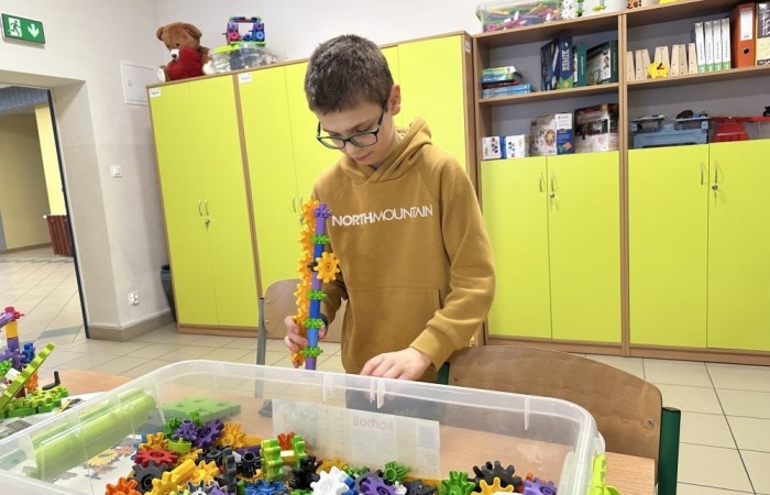 26 lutego w naszej szkole odbył się wyjątkowy DZIEŃ OTWARTY, podczas którego mieliśmy przyjemność gościć przedszkolaków, przyszłych uczniów oraz ich rodziców. Była to doskonała okazja, aby poczuć atmosferę naszej szkoły, poznać jej ofertę edukacyjną i odkryć to, co czyni ją miejscem pełnym pasji, wiedzy i radości.
Zwiedzanie naszej placówki obejmowało sale przedmiotowe, bibliotekę, stołówkę, świetlicę oraz małą salę gimnastyczną, gdzie można było na własnej skórze poczuć rytm codziennego życia naszej szkolnej społeczności.
Na odwiedzających czekało mnóstwo niespodzianek! Zachętą do działania były pieczątki, które najmłodsi otrzymywali w nagrodę za wykonanie przeróżnych zadań. W sali gimnastycznej na uczestników czekały ekscytujące konkurencje sprawnościowe, a w pracowni kulinarnej – pachnące i chrupiące gofry własnej roboty. Młodzi odkrywcy mieli okazję badać świat przez mikroskop, eksperymentować z interaktywnymi robotami Photon oraz brać udział w zajęciach z robotyki. Z kolei miłośnicy sztuki mogli tworzyć piękne dzieła na warsztatach plastycznych i origami, a najmłodsi cieszyli się malowaniem twarzy.
Nie zabrakło także wyzwań dla bystrego umysłu! Gry i zabawy językowe, rebusy oraz polonistyczne łamigłówki rozbudzały wyobraźnię i rozwijały umiejętności językowe. Wesoła „Gimnastyka buzi i języka” sprawiła, że ćwiczenie dykcji stało się czystą przyjemnością. Ogromnym zainteresowaniem cieszyły się również gry planszowe, które dostarczyły mnóstwa radości i emocjonującej rywalizacji. Dodatkowo, zabawy z chustą Klanza okazały się świetnym sposobem na integrację i wspólną zabawę pełną śmiechu.
Aktywne zwiedzanie stało się więc okazją do rozwijania ciekawości świata, nabywania nowych umiejętności, pobudzania w najmłodszych kreatywności oraz odczuwania satysfakcji z osiągniętego sukcesu.