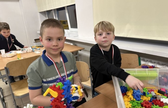 26 lutego w naszej szkole odbył się wyjątkowy DZIEŃ OTWARTY, podczas którego mieliśmy przyjemność gościć przedszkolaków, przyszłych uczniów oraz ich rodziców. Była to doskonała okazja, aby poczuć atmosferę naszej szkoły, poznać jej ofertę edukacyjną i odkryć to, co czyni ją miejscem pełnym pasji, wiedzy i radości.
Zwiedzanie naszej placówki obejmowało sale przedmiotowe, bibliotekę, stołówkę, świetlicę oraz małą salę gimnastyczną, gdzie można było na własnej skórze poczuć rytm codziennego życia naszej szkolnej społeczności.
Na odwiedzających czekało mnóstwo niespodzianek! Zachętą do działania były pieczątki, które najmłodsi otrzymywali w nagrodę za wykonanie przeróżnych zadań. W sali gimnastycznej na uczestników czekały ekscytujące konkurencje sprawnościowe, a w pracowni kulinarnej – pachnące i chrupiące gofry własnej roboty. Młodzi odkrywcy mieli okazję badać świat przez mikroskop, eksperymentować z interaktywnymi robotami Photon oraz brać udział w zajęciach z robotyki. Z kolei miłośnicy sztuki mogli tworzyć piękne dzieła na warsztatach plastycznych i origami, a najmłodsi cieszyli się malowaniem twarzy.
Nie zabrakło także wyzwań dla bystrego umysłu! Gry i zabawy językowe, rebusy oraz polonistyczne łamigłówki rozbudzały wyobraźnię i rozwijały umiejętności językowe. Wesoła „Gimnastyka buzi i języka” sprawiła, że ćwiczenie dykcji stało się czystą przyjemnością. Ogromnym zainteresowaniem cieszyły się również gry planszowe, które dostarczyły mnóstwa radości i emocjonującej rywalizacji. Dodatkowo, zabawy z chustą Klanza okazały się świetnym sposobem na integrację i wspólną zabawę pełną śmiechu.
Aktywne zwiedzanie stało się więc okazją do rozwijania ciekawości świata, nabywania nowych umiejętności, pobudzania w najmłodszych kreatywności oraz odczuwania satysfakcji z osiągniętego sukcesu.