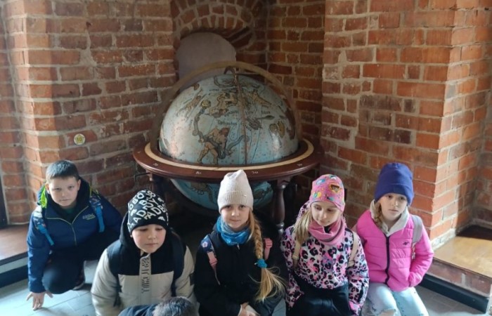 10 kwietnia uczniowie klas pierwszych wyruszyli na wyjątkową wycieczkę do Fromborka, miasta związanego z postacią Mikołaja Kopernika – wybitnego astronoma, który „wstrzymał Słońce, ruszył Ziemię”. Największą atrakcją było oczywiście Planetarium, gdzie dzieci mogły przenieść się w sam środek kosmosu – zobaczyć planety, gwiazdy i dowiedzieć się, jak wygląda Wszechświat oczami współczesnych odkrywców. Nie zabrakło też spaceru po wzgórzu katedralnym i odrobiny historii – uczniowie odwiedzili miejsca, w których żył i pracował sam Kopernik.
Z nową wiedzą, mnóstwem wrażeń i szerokimi uśmiechami wróciliśmy do szkoły. To była naprawdę udana podróż – zarówno w czasie, jak i przestrzeni. Zapraszamy do obejrzenia zdjęć z naszej wyprawy.