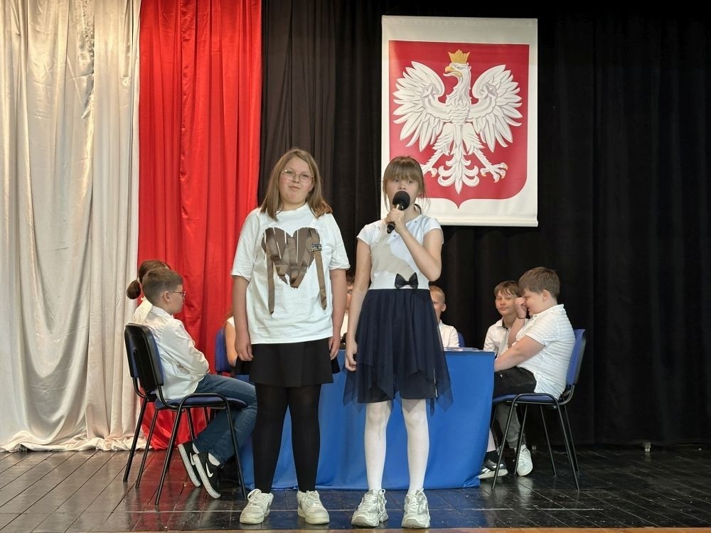 W przeddzień rocznicy uchwalenia Konstytucji 3 Maja w naszej szkole z tej okazji odbył się akademia przygotowana przez uczniów kl. IV a i IV b przy współudziale zespołu wokalnego.
Jego celem było budzenie wrażliwości uczniów na święta narodowe oraz kształtowanie postaw patriotycznych.
Akademia rozpoczęła się uroczystym odśpiewaniem hymnu państwowego. Następnie uczniowie klas czwartych przybliżyli wydarzenia tamtych dni. Zwrócono uwagę na poszanowanie barw narodowych przypominając, iż 2 maja obchodzimy Święto Flagi.
Korzystając z okazji,  pani dyrektor Agnieszka Cieklińska pogratulowała  Marcelowi Chełstowskiemu – Lanzer, uczniowi kl. VII b,  uzyskania  tytułu laureata w Konkursie z  Języka Niemieckiego organizowanego  przez Warmińsko – Mazurskiego Kuratora Oświaty w Olsztynie i wręczyła pamiątkowy dyplom.
Pani dyrektor wręczyła również dyplom pani Annie Cieśli, nauczycielce języka niemieckiego, dziękując za przygotowanie ucznia do konkursu.
Na zakończenie akademii pani Agnieszka Cieklińska życzyła całej społeczności szkolnej radosnego świętowana majowych dni.
