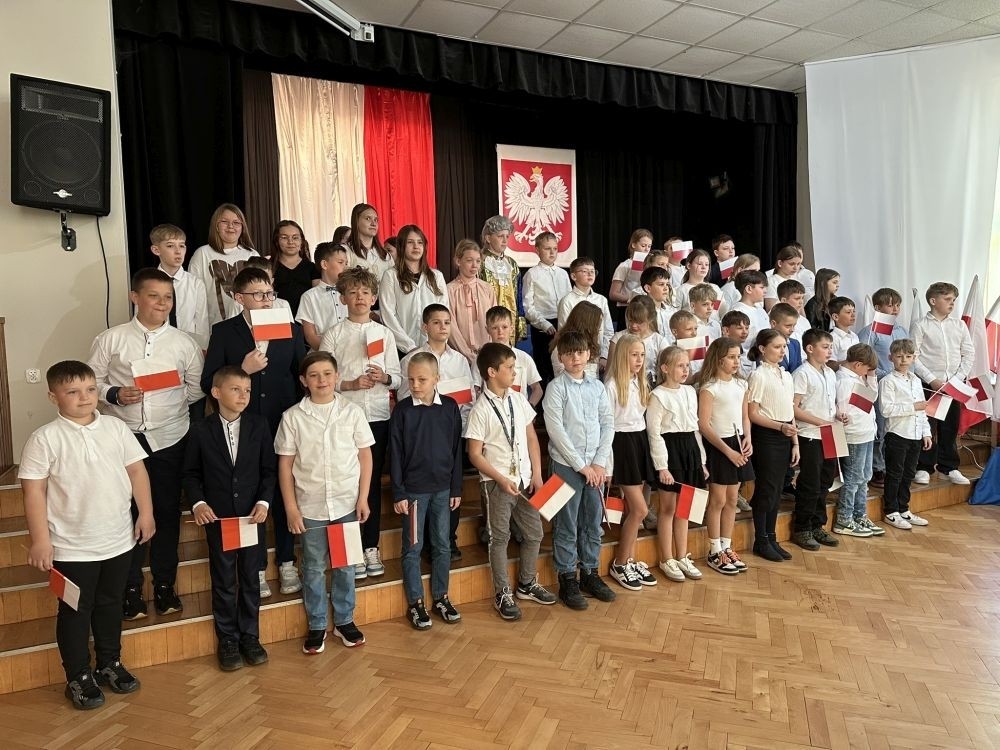 W przeddzień rocznicy uchwalenia Konstytucji 3 Maja w naszej szkole z tej okazji odbył się akademia przygotowana przez uczniów kl. IV a i IV b przy współudziale zespołu wokalnego.
Jego celem było budzenie wrażliwości uczniów na święta narodowe oraz kształtowanie postaw patriotycznych.
Akademia rozpoczęła się uroczystym odśpiewaniem hymnu państwowego. Następnie uczniowie klas czwartych przybliżyli wydarzenia tamtych dni. Zwrócono uwagę na poszanowanie barw narodowych przypominając, iż 2 maja obchodzimy Święto Flagi.
Korzystając z okazji,  pani dyrektor Agnieszka Cieklińska pogratulowała  Marcelowi Chełstowskiemu – Lanzer, uczniowi kl. VII b,  uzyskania  tytułu laureata w Konkursie z  Języka Niemieckiego organizowanego  przez Warmińsko – Mazurskiego Kuratora Oświaty w Olsztynie i wręczyła pamiątkowy dyplom.
Pani dyrektor wręczyła również dyplom pani Annie Cieśli, nauczycielce języka niemieckiego, dziękując za przygotowanie ucznia do konkursu.
Na zakończenie akademii pani Agnieszka Cieklińska życzyła całej społeczności szkolnej radosnego świętowana majowych dni.

