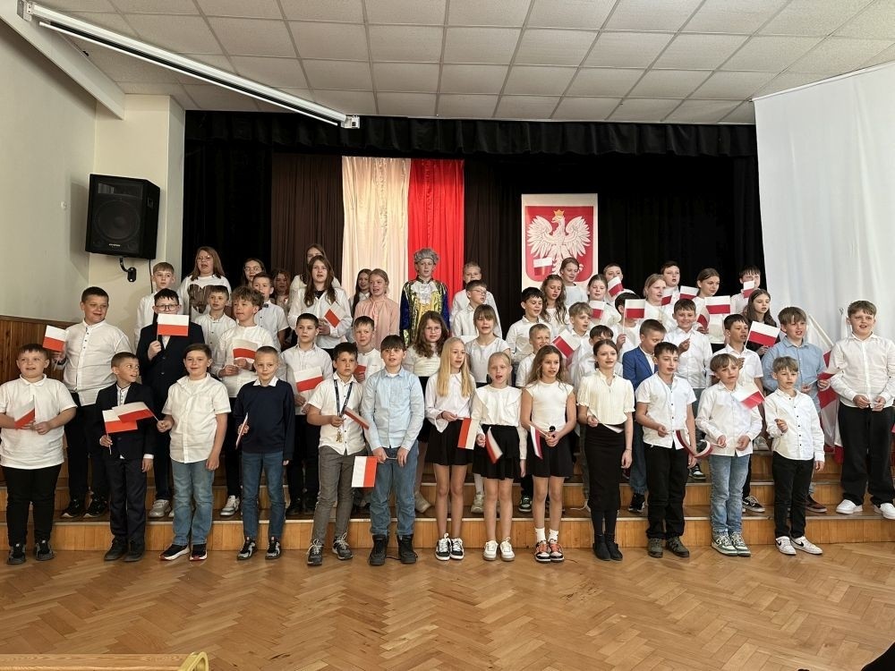 W przeddzień rocznicy uchwalenia Konstytucji 3 Maja w naszej szkole z tej okazji odbył się akademia przygotowana przez uczniów kl. IV a i IV b przy współudziale zespołu wokalnego.
Jego celem było budzenie wrażliwości uczniów na święta narodowe oraz kształtowanie postaw patriotycznych.
Akademia rozpoczęła się uroczystym odśpiewaniem hymnu państwowego. Następnie uczniowie klas czwartych przybliżyli wydarzenia tamtych dni. Zwrócono uwagę na poszanowanie barw narodowych przypominając, iż 2 maja obchodzimy Święto Flagi.
Korzystając z okazji,  pani dyrektor Agnieszka Cieklińska pogratulowała  Marcelowi Chełstowskiemu – Lanzer, uczniowi kl. VII b,  uzyskania  tytułu laureata w Konkursie z  Języka Niemieckiego organizowanego  przez Warmińsko – Mazurskiego Kuratora Oświaty w Olsztynie i wręczyła pamiątkowy dyplom.
Pani dyrektor wręczyła również dyplom pani Annie Cieśli, nauczycielce języka niemieckiego, dziękując za przygotowanie ucznia do konkursu.
Na zakończenie akademii pani Agnieszka Cieklińska życzyła całej społeczności szkolnej radosnego świętowana majowych dni.
