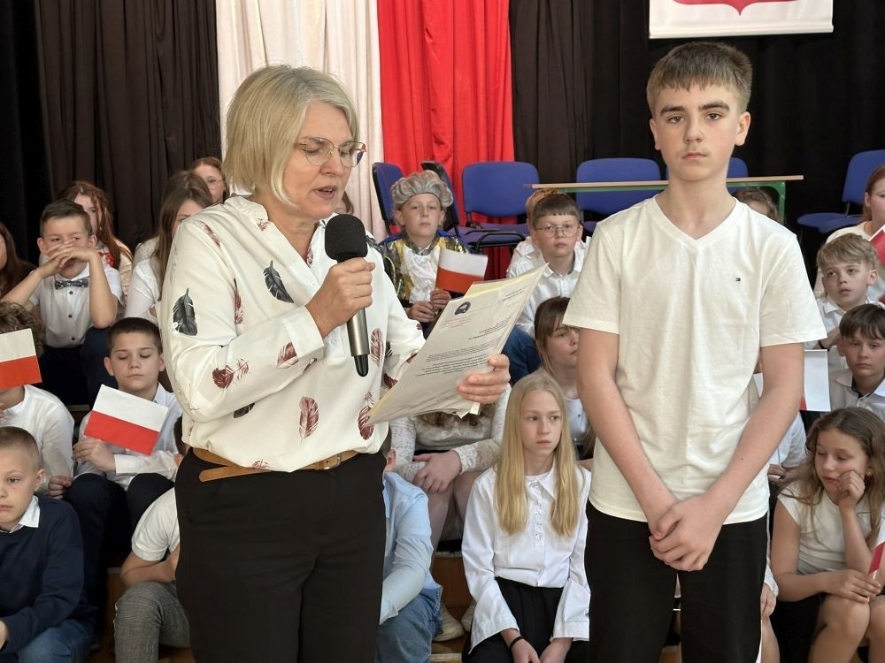 W przeddzień rocznicy uchwalenia Konstytucji 3 Maja w naszej szkole z tej okazji odbył się akademia przygotowana przez uczniów kl. IV a i IV b przy współudziale zespołu wokalnego.
Jego celem było budzenie wrażliwości uczniów na święta narodowe oraz kształtowanie postaw patriotycznych.
Akademia rozpoczęła się uroczystym odśpiewaniem hymnu państwowego. Następnie uczniowie klas czwartych przybliżyli wydarzenia tamtych dni. Zwrócono uwagę na poszanowanie barw narodowych przypominając, iż 2 maja obchodzimy Święto Flagi.
Korzystając z okazji,  pani dyrektor Agnieszka Cieklińska pogratulowała  Marcelowi Chełstowskiemu – Lanzer, uczniowi kl. VII b,  uzyskania  tytułu laureata w Konkursie z  Języka Niemieckiego organizowanego  przez Warmińsko – Mazurskiego Kuratora Oświaty w Olsztynie i wręczyła pamiątkowy dyplom.
Pani dyrektor wręczyła również dyplom pani Annie Cieśli, nauczycielce języka niemieckiego, dziękując za przygotowanie ucznia do konkursu.
Na zakończenie akademii pani Agnieszka Cieklińska życzyła całej społeczności szkolnej radosnego świętowana majowych dni.
