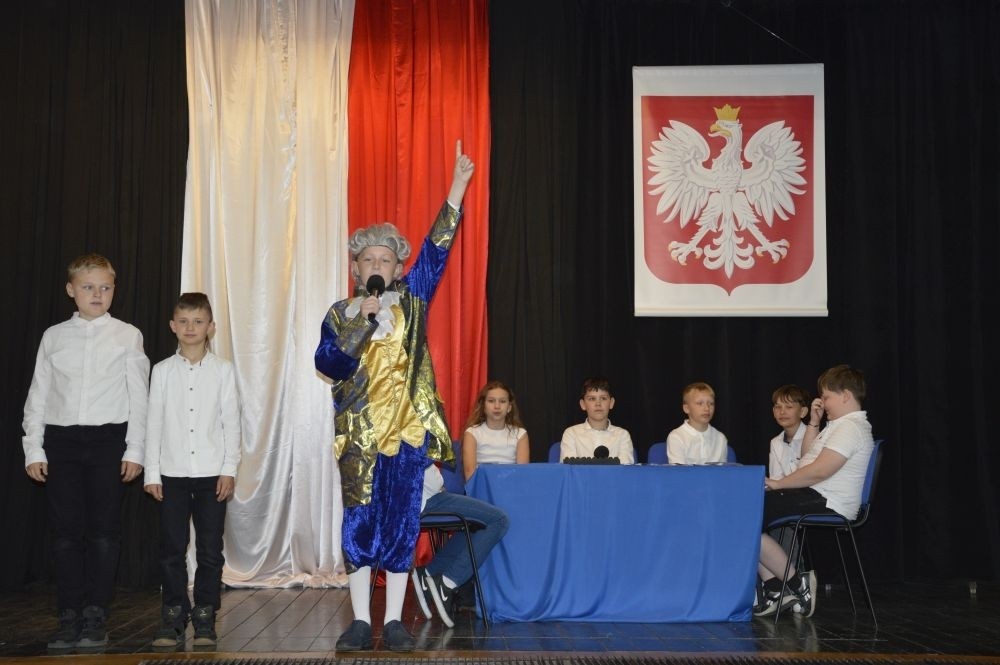 W przeddzień rocznicy uchwalenia Konstytucji 3 Maja w naszej szkole z tej okazji odbył się akademia przygotowana przez uczniów kl. IV a i IV b przy współudziale zespołu wokalnego.
Jego celem było budzenie wrażliwości uczniów na święta narodowe oraz kształtowanie postaw patriotycznych.
Akademia rozpoczęła się uroczystym odśpiewaniem hymnu państwowego. Następnie uczniowie klas czwartych przybliżyli wydarzenia tamtych dni. Zwrócono uwagę na poszanowanie barw narodowych przypominając, iż 2 maja obchodzimy Święto Flagi.
Korzystając z okazji,  pani dyrektor Agnieszka Cieklińska pogratulowała  Marcelowi Chełstowskiemu – Lanzer, uczniowi kl. VII b,  uzyskania  tytułu laureata w Konkursie z  Języka Niemieckiego organizowanego  przez Warmińsko – Mazurskiego Kuratora Oświaty w Olsztynie i wręczyła pamiątkowy dyplom.
Pani dyrektor wręczyła również dyplom pani Annie Cieśli, nauczycielce języka niemieckiego, dziękując za przygotowanie ucznia do konkursu.
Na zakończenie akademii pani Agnieszka Cieklińska życzyła całej społeczności szkolnej radosnego świętowana majowych dni.
