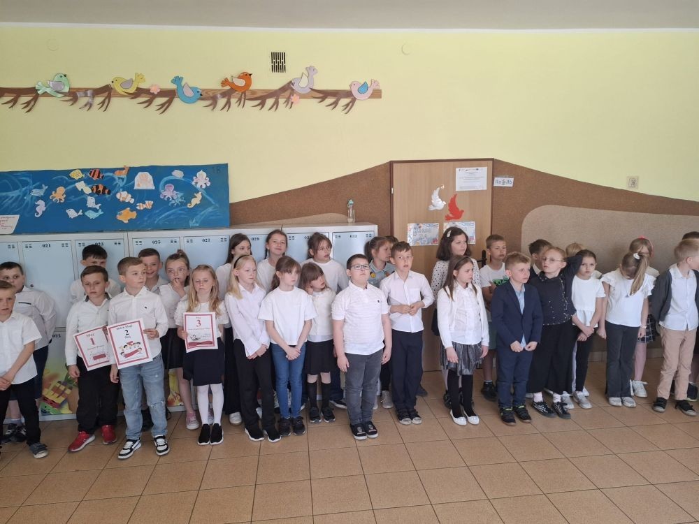 Dziś na szkolnym dziedzińcu zapanowała wyjątkowa, podniosła atmosfera. Uczniowie klas młodszych, ubrani w galowe stroje, z dumą stanęli do wspólnego odśpiewania hymnu Polski. W ich dłoniach powiewały biało-czerwone flagi, a serca wypełniała duma i szacunek dla Ojczyzny.
W ten sposób rozpoczęliśmy szkolne obchody zbliżających się świąt majowych – Święta Pracy (1 maja), Dnia Flagi Rzeczypospolitej Polskiej (2 maja) oraz Święta Konstytucji 3 Maja. To dla nas ważna lekcja historii, patriotyzmu i wspólnoty.

