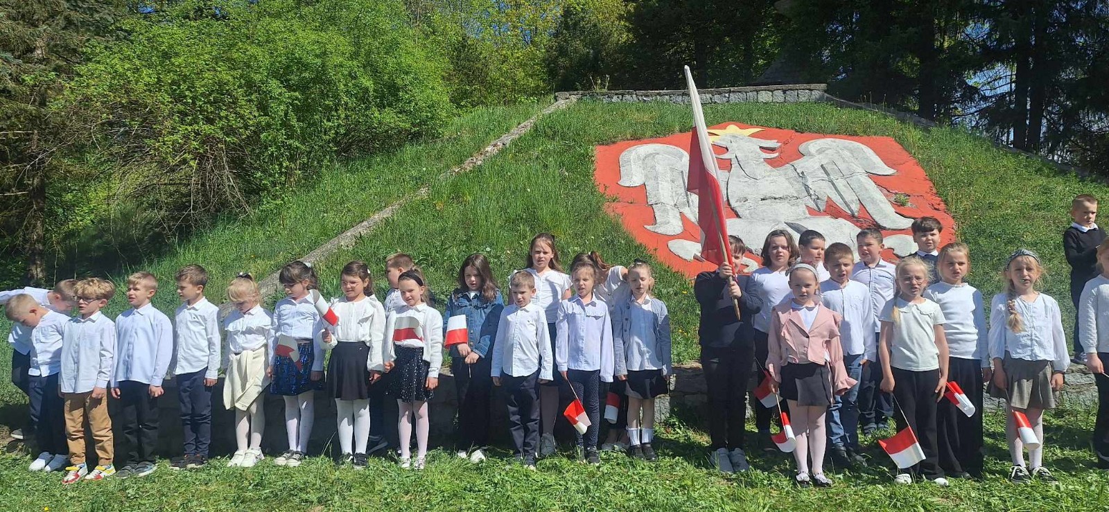 Dziś na szkolnym dziedzińcu zapanowała wyjątkowa, podniosła atmosfera. Uczniowie klas młodszych, ubrani w galowe stroje, z dumą stanęli do wspólnego odśpiewania hymnu Polski. W ich dłoniach powiewały biało-czerwone flagi, a serca wypełniała duma i szacunek dla Ojczyzny.
W ten sposób rozpoczęliśmy szkolne obchody zbliżających się świąt majowych – Święta Pracy (1 maja), Dnia Flagi Rzeczypospolitej Polskiej (2 maja) oraz Święta Konstytucji 3 Maja. To dla nas ważna lekcja historii, patriotyzmu i wspólnoty.

