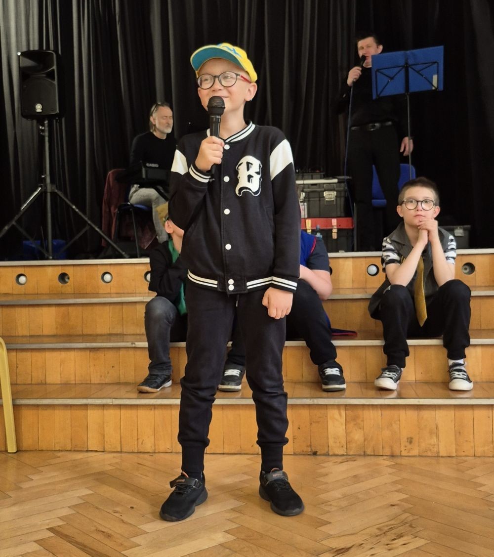 Dziś nasza szkoła na chwilę zamieniła się w scenę pełną świateł, dźwięków i... gwiazdorskiego blasku. Wszystko za sprawą koncertu, podczas którego rozstrzygnęliśmy szkolny konkurs wiedzy muzycznej. Temat przewodni? Życie muzycznej gwiazdy – a nasi uczniowie potraktowali to bardzo serio! Wybrani aktorzy-amatorzy (choć po dzisiejszym dniu to już prawie zawodowcy) wcielili się w rolę słynnego artysty i dali prawdziwy popis nie tylko wokalny. Były piosenki, taniec, emocje, dramat sceniczny i masa dobrej zabawy. Publiczność śpiewała i tańczyła razem z nimi, jak na prawdziwym koncercie. Gdyby ktoś zapytał, co dziś działo się w naszej szkole – odpowiedź jest prosta: muzyka, emocje i zabawa na całego.