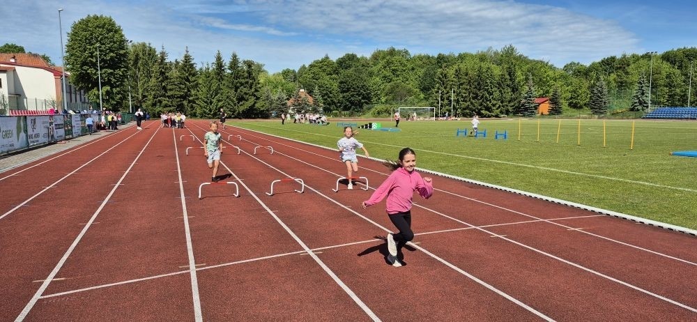 Tegoroczne obchody rozpoczęliśmy twórczo – od przygotowania plakatów „Mistrz zdrowia”. Po tej kreatywnej rozgrzewce przyszedł czas na sportowe emocje. Uroczyste otwarcie było tylko wstępem do licznych atrakcji, które czekały na dzieci na stadionie. Dzięki zaangażowaniu pana Piotra Borysewicza i sportowców z KS Polonia Pasłęk sekcji lekkoatletycznej, uczniowie mogli spróbować swoich sił w biegu przez płotki, rzucie piłeczką oraz torze przeszkód w stylu „Ninja Warrior”. Ogromną atrakcją była również wizyta strażaków z JRG 3 w Pasłęku, którzy zapewnili dzieciom wodno-pianową zabawę. Radość na twarzach uczestników mówiła sama za siebie. Na wszystkich zgłodniałych czekały pyszności, w tym słodka wata cukrowa, serwowana przez Panie z Koła Gospodyń Wiejskich w Borzynowie. Szczególne podziękowania kierujemy do niezastąpionych Rodziców – za wsparcie organizacyjne, opiekę podczas wydarzenia oraz przygotowanie dodatkowych atrakcji: plenerowego studia malowania twarzy i tatuaży. Na zakończenie nikt nie wyszedł z pustymi rękami – niezależnie od wyników konkursów każdy uczeń otrzymał drobny upominek i medal. To wyjątkowe święto pełne radości i zabawy już za nami, więc zaczynamy odliczanie do kolejnego Dnia Dziecka!