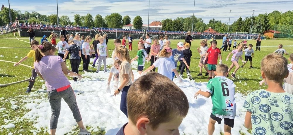 Tegoroczne obchody rozpoczęliśmy twórczo – od przygotowania plakatów „Mistrz zdrowia”. Po tej kreatywnej rozgrzewce przyszedł czas na sportowe emocje. Uroczyste otwarcie było tylko wstępem do licznych atrakcji, które czekały na dzieci na stadionie. Dzięki zaangażowaniu pana Piotra Borysewicza i sportowców z KS Polonia Pasłęk sekcji lekkoatletycznej, uczniowie mogli spróbować swoich sił w biegu przez płotki, rzucie piłeczką oraz torze przeszkód w stylu „Ninja Warrior”. Ogromną atrakcją była również wizyta strażaków z JRG 3 w Pasłęku, którzy zapewnili dzieciom wodno-pianową zabawę. Radość na twarzach uczestników mówiła sama za siebie. Na wszystkich zgłodniałych czekały pyszności, w tym słodka wata cukrowa, serwowana przez Panie z Koła Gospodyń Wiejskich w Borzynowie. Szczególne podziękowania kierujemy do niezastąpionych Rodziców – za wsparcie organizacyjne, opiekę podczas wydarzenia oraz przygotowanie dodatkowych atrakcji: plenerowego studia malowania twarzy i tatuaży. Na zakończenie nikt nie wyszedł z pustymi rękami – niezależnie od wyników konkursów każdy uczeń otrzymał drobny upominek i medal. To wyjątkowe święto pełne radości i zabawy już za nami, więc zaczynamy odliczanie do kolejnego Dnia Dziecka!