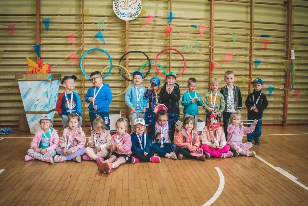 2 czerwca w naszym przedszkolu odbyły się wyjątkowe obchody Dnia Dziecka. W tym roku postawiliśmy na ruch, zabawę i zdrową rywalizację, organizując Sportowy Dzień Dziecka.
Dzień rozpoczęliśmy na Stadionie Miejskim oraz powitania przez panią Dyrektor Agnieszkę Cieklińską i złożenia życzeń z okazji Dnia Dziecka. Następnie wzięliśmy udział w XI edycji Ogólnopolskiego Maratonu Przedszkolaków „Sprintem do maratonu”. Jesteśmy dumne, że nasze przedszkolaki pokonały łącznie aż  3,8 km ! Dalszą część wydarzenia dzieci rywalizowały w różnych konkurencjach: bieg po torze, bieg z przeszkodami, skoki przez płotki czy rzut do celu. Każde dziecko mogło wykazać się sprawnością, zręcznością i współpracą w grupie.
Nie zabrakło także strefy kibica – dzieci dopingowały się nawzajem, a wychowawcy nie szczędzili braw i motywujących okrzyków. Dzięki wsparciu Stowarzyszeniu Przyjaciół Pasłęckiej Dwójki i Koła Gospodyń Wiejskich w Borzynowie w przerwach pomiędzy konkurencjami na dzieci czekały przekąski: owoce, woda, lody, wata cukrowa oraz popcorn.
Na zakończenie wszyscy uczestnicy otrzymali pamiątkowe medale wręczane przez panią Wicedyrektor  Anettę Daszkowską. Radość była ogromna dla dzieci liczyła się przede wszystkim dobra zabawa i wspólnie spędzony czas.
