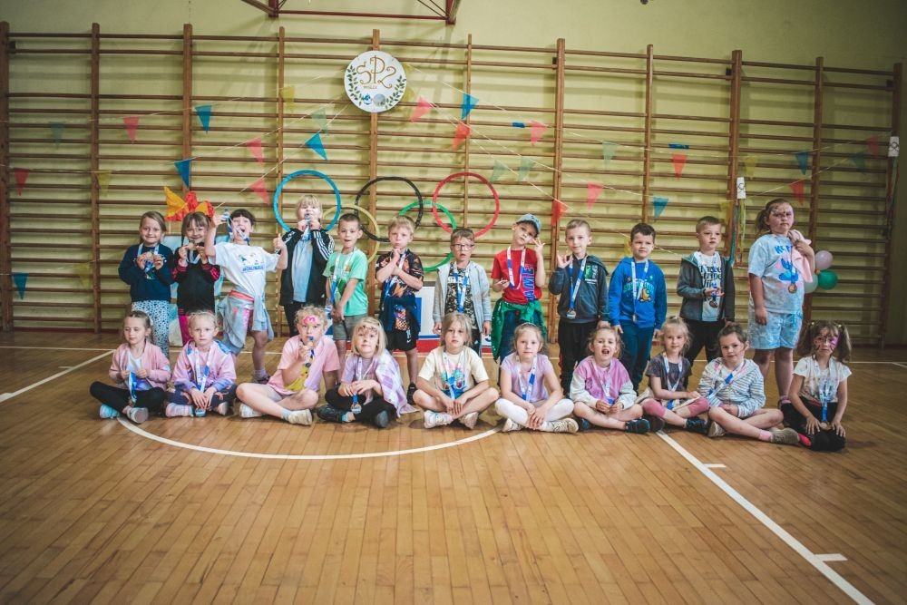 2 czerwca w naszym przedszkolu odbyły się wyjątkowe obchody Dnia Dziecka. W tym roku postawiliśmy na ruch, zabawę i zdrową rywalizację, organizując Sportowy Dzień Dziecka.
Dzień rozpoczęliśmy na Stadionie Miejskim oraz powitania przez panią Dyrektor Agnieszkę Cieklińską i złożenia życzeń z okazji Dnia Dziecka. Następnie wzięliśmy udział w XI edycji Ogólnopolskiego Maratonu Przedszkolaków „Sprintem do maratonu”. Jesteśmy dumne, że nasze przedszkolaki pokonały łącznie aż  3,8 km ! Dalszą część wydarzenia dzieci rywalizowały w różnych konkurencjach: bieg po torze, bieg z przeszkodami, skoki przez płotki czy rzut do celu. Każde dziecko mogło wykazać się sprawnością, zręcznością i współpracą w grupie.
Nie zabrakło także strefy kibica – dzieci dopingowały się nawzajem, a wychowawcy nie szczędzili braw i motywujących okrzyków. Dzięki wsparciu Stowarzyszeniu Przyjaciół Pasłęckiej Dwójki i Koła Gospodyń Wiejskich w Borzynowie w przerwach pomiędzy konkurencjami na dzieci czekały przekąski: owoce, woda, lody, wata cukrowa oraz popcorn.
Na zakończenie wszyscy uczestnicy otrzymali pamiątkowe medale wręczane przez panią Wicedyrektor  Anettę Daszkowską. Radość była ogromna dla dzieci liczyła się przede wszystkim dobra zabawa i wspólnie spędzony czas.

