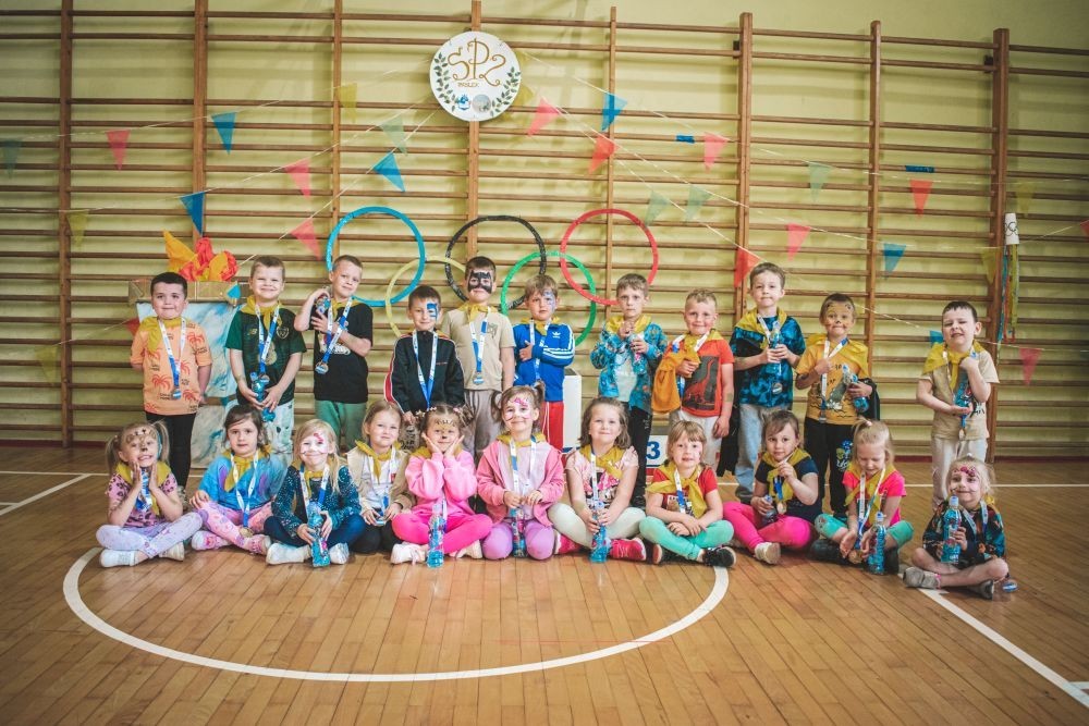 2 czerwca w naszym przedszkolu odbyły się wyjątkowe obchody Dnia Dziecka. W tym roku postawiliśmy na ruch, zabawę i zdrową rywalizację, organizując Sportowy Dzień Dziecka.
Dzień rozpoczęliśmy na Stadionie Miejskim oraz powitania przez panią Dyrektor Agnieszkę Cieklińską i złożenia życzeń z okazji Dnia Dziecka. Następnie wzięliśmy udział w XI edycji Ogólnopolskiego Maratonu Przedszkolaków „Sprintem do maratonu”. Jesteśmy dumne, że nasze przedszkolaki pokonały łącznie aż  3,8 km ! Dalszą część wydarzenia dzieci rywalizowały w różnych konkurencjach: bieg po torze, bieg z przeszkodami, skoki przez płotki czy rzut do celu. Każde dziecko mogło wykazać się sprawnością, zręcznością i współpracą w grupie.
Nie zabrakło także strefy kibica – dzieci dopingowały się nawzajem, a wychowawcy nie szczędzili braw i motywujących okrzyków. Dzięki wsparciu Stowarzyszeniu Przyjaciół Pasłęckiej Dwójki i Koła Gospodyń Wiejskich w Borzynowie w przerwach pomiędzy konkurencjami na dzieci czekały przekąski: owoce, woda, lody, wata cukrowa oraz popcorn.
Na zakończenie wszyscy uczestnicy otrzymali pamiątkowe medale wręczane przez panią Wicedyrektor  Anettę Daszkowską. Radość była ogromna dla dzieci liczyła się przede wszystkim dobra zabawa i wspólnie spędzony czas.
