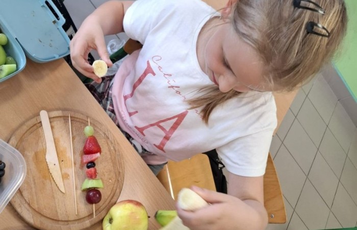 W klasie 2a zrobiło się kolorowo, zdrowo i pysznie. Uczniowie z ogromnym zaangażowaniem przygotowywali owocowe szaszłyki, które zachwycały nie tylko smakiem, ale też wyglądem. Na stołach królowały ulubione owoce dzieci: truskawki, winogrona, banany, kiwi, jabłka i wiele innych. Każdy samodzielnie kroił owoce i tworzył własne, kreatywne kompozycje. To była nie tylko smakowita zabawa, ale również świetna okazja do rozmów o zdrowym odżywianiu oraz nauki współpracy.