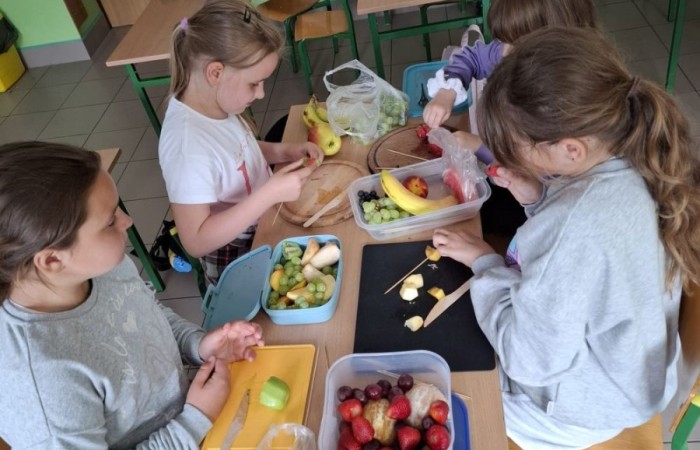 W klasie 2a zrobiło się kolorowo, zdrowo i pysznie. Uczniowie z ogromnym zaangażowaniem przygotowywali owocowe szaszłyki, które zachwycały nie tylko smakiem, ale też wyglądem. Na stołach królowały ulubione owoce dzieci: truskawki, winogrona, banany, kiwi, jabłka i wiele innych. Każdy samodzielnie kroił owoce i tworzył własne, kreatywne kompozycje. To była nie tylko smakowita zabawa, ale również świetna okazja do rozmów o zdrowym odżywianiu oraz nauki współpracy.