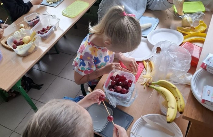 W klasie 2a zrobiło się kolorowo, zdrowo i pysznie. Uczniowie z ogromnym zaangażowaniem przygotowywali owocowe szaszłyki, które zachwycały nie tylko smakiem, ale też wyglądem. Na stołach królowały ulubione owoce dzieci: truskawki, winogrona, banany, kiwi, jabłka i wiele innych. Każdy samodzielnie kroił owoce i tworzył własne, kreatywne kompozycje. To była nie tylko smakowita zabawa, ale również świetna okazja do rozmów o zdrowym odżywianiu oraz nauki współpracy.