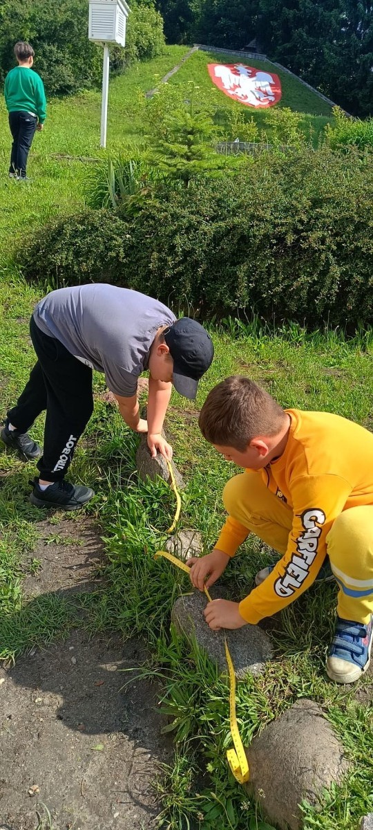 Klasa 1a ruszyła dziś z miarkami krawieckimi na szkolny plac, żeby sprawdzić, ile mierzy… brama, śmietnik i krawężnik. Dzięki praktycznym zajęciom dzieci nie tylko utrwaliły pojęcia związane z długością, ale też świetnie się bawiły mierząc wszystko, co tylko dało się zmierzyć. Takie lekcje to prawdziwa frajda – nauka przez działanie i odkrywanie świata wokół nas.
