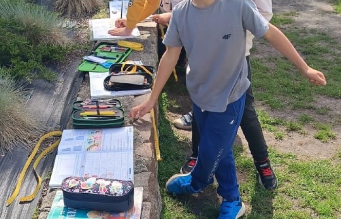 Klasa 1a ruszyła dziś z miarkami krawieckimi na szkolny plac, żeby sprawdzić, ile mierzy… brama, śmietnik i krawężnik. Dzięki praktycznym zajęciom dzieci nie tylko utrwaliły pojęcia związane z długością, ale też świetnie się bawiły mierząc wszystko, co tylko dało się zmierzyć. Takie lekcje to prawdziwa frajda – nauka przez działanie i odkrywanie świata wokół nas.