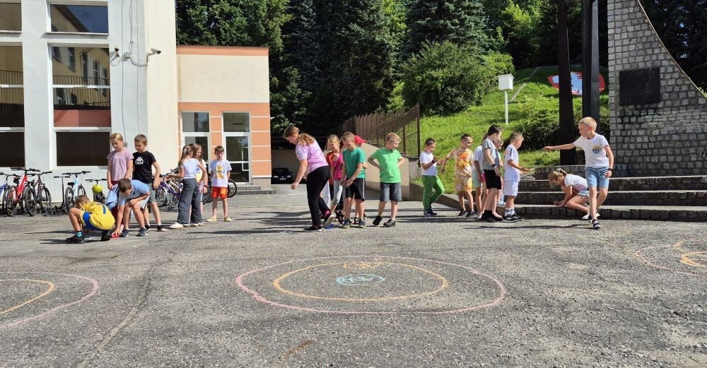 Dziś uczniowie klasy 2b wybrali się na plac przed szkołę, gdzie połączyli przyjemne z pożytecznym. Podczas zabawy w rzuty woreczkiem do celu dzieci nie tylko świetnie się bawiły, ale również ćwiczyły swoją sprawność rachunkową – dodając zdobyte przez grupy punkty.  Radość, ruch i nauka w jednym – właśnie tak lubimy się uczyć.