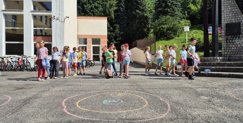 Dziś uczniowie klasy 2b wybrali się na plac przed szkołę, gdzie połączyli przyjemne z pożytecznym. Podczas zabawy w rzuty woreczkiem do celu dzieci nie tylko świetnie się bawiły, ale również ćwiczyły swoją sprawność rachunkową – dodając zdobyte przez grupy punkty.  Radość, ruch i nauka w jednym – właśnie tak lubimy się uczyć.