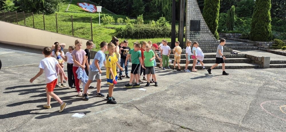 Dziś uczniowie klasy 2b wybrali się na plac przed szkołę, gdzie połączyli przyjemne z pożytecznym. Podczas zabawy w rzuty woreczkiem do celu dzieci nie tylko świetnie się bawiły, ale również ćwiczyły swoją sprawność rachunkową – dodając zdobyte przez grupy punkty.  Radość, ruch i nauka w jednym – właśnie tak lubimy się uczyć.