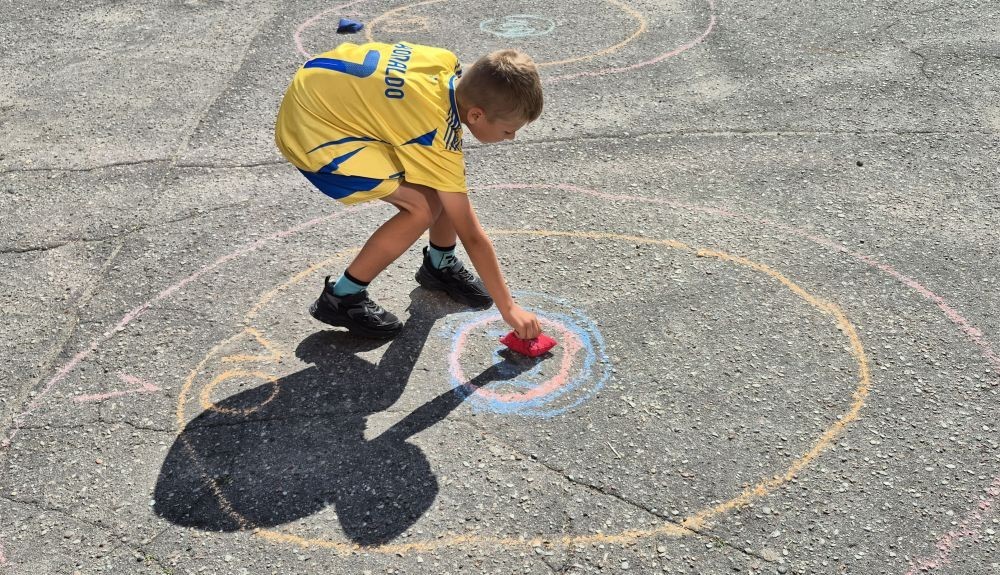Dziś uczniowie klasy 2b wybrali się na plac przed szkołę, gdzie połączyli przyjemne z pożytecznym. Podczas zabawy w rzuty woreczkiem do celu dzieci nie tylko świetnie się bawiły, ale również ćwiczyły swoją sprawność rachunkową – dodając zdobyte przez grupy punkty.  Radość, ruch i nauka w jednym – właśnie tak lubimy się uczyć.