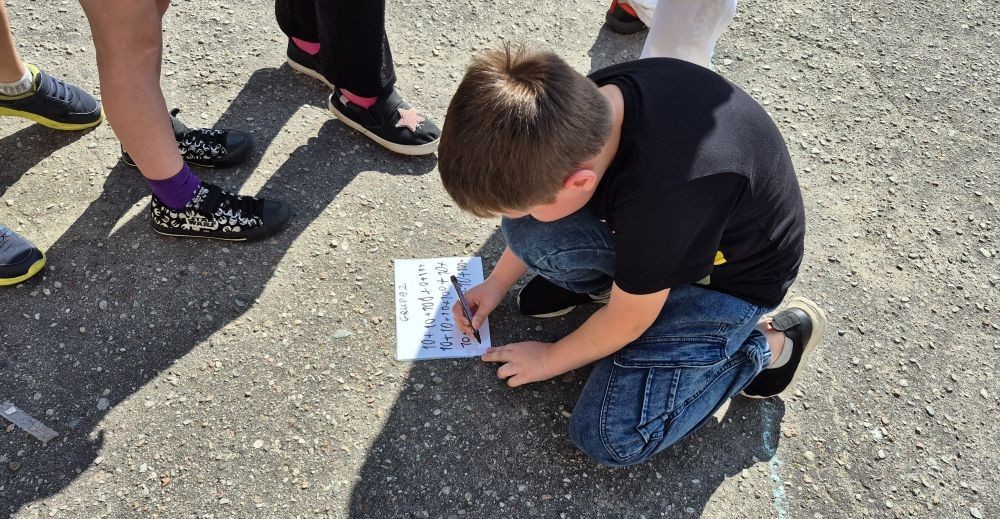 Dziś uczniowie klasy 2b wybrali się na plac przed szkołę, gdzie połączyli przyjemne z pożytecznym. Podczas zabawy w rzuty woreczkiem do celu dzieci nie tylko świetnie się bawiły, ale również ćwiczyły swoją sprawność rachunkową – dodając zdobyte przez grupy punkty.  Radość, ruch i nauka w jednym – właśnie tak lubimy się uczyć.