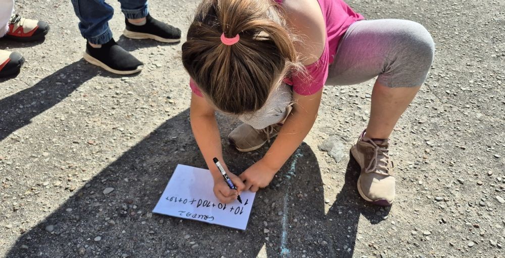 Dziś uczniowie klasy 2b wybrali się na plac przed szkołę, gdzie połączyli przyjemne z pożytecznym. Podczas zabawy w rzuty woreczkiem do celu dzieci nie tylko świetnie się bawiły, ale również ćwiczyły swoją sprawność rachunkową – dodając zdobyte przez grupy punkty.  Radość, ruch i nauka w jednym – właśnie tak lubimy się uczyć.