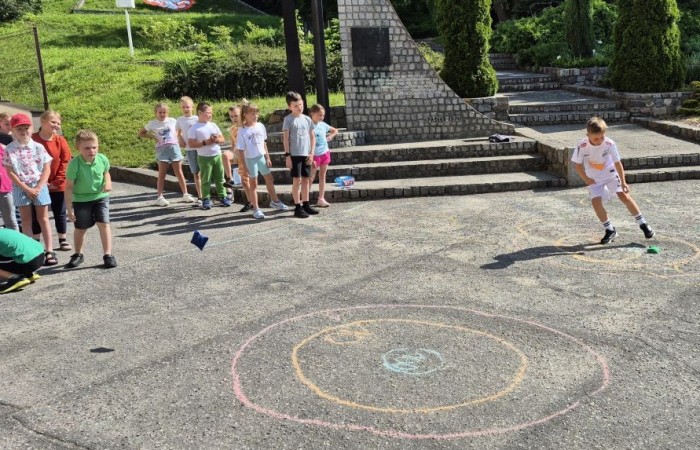 Dziś uczniowie klasy 2b wybrali się na plac przed szkołę, gdzie połączyli przyjemne z pożytecznym. Podczas zabawy w rzuty woreczkiem do celu dzieci nie tylko świetnie się bawiły, ale również ćwiczyły swoją sprawność rachunkową – dodając zdobyte przez grupy punkty.  Radość, ruch i nauka w jednym – właśnie tak lubimy się uczyć.