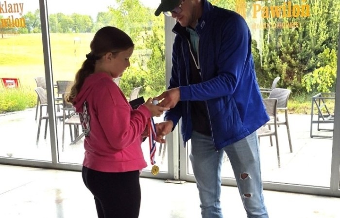 Choć pogoda nie do końca dopisała, uczniowie klasy 2b spędzili niezwykle ciekawy dzień w Sand Valley Golf Resort w Pasłęku. Dzieci miały okazję: dowiedzieć się, na czym polega gra w golfa, obejrzeć profesjonalny sprzęt wykorzystywany w tym sporcie, przejechać się meleksem po rozległym terenie, spróbować pysznych frytek i orzeźwiającej lemoniady serwowanych w tutejszej restauracji. Na zakończenie każdy uczestnik otrzymał pamiątkowy medal, piłeczkę golfową i drobne upominki. Niestety, z powodu deszczu nie udało się przeprowadzić treningu uderzeń piłeczki… ale kto wie – może następnym razem pogoda będzie łaskawsza.