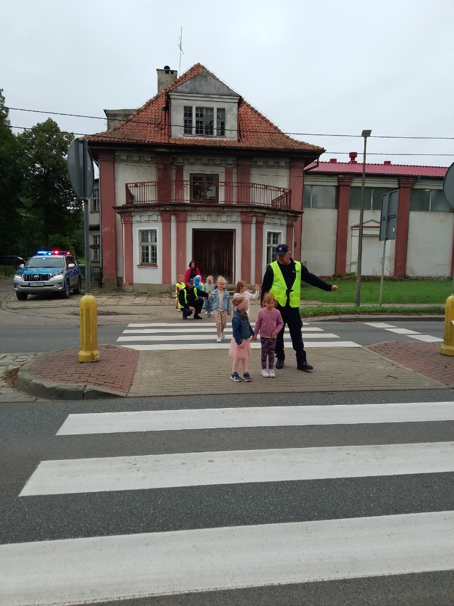 Dzieci z grup starszych Sówki, Leśne skrzaty oraz Biedronki odwiedzili funkcjonariusze policji drogowej , którzy przeprowadzili zajęcia edukacyjne na temat bezpieczeństwa w ruchu ulicznym. Wydarzenie odbyło się w ramach zajęć ,,Moja droga do przedszkola”, której celem jest kształtowanie prawidłowych nawyków i świadomości wśród najmłodszych uczestników ruchu drogowego. Policjanci opowiedzieli przedszkolakom o zasadach bezpiecznego przechodzenia przez jezdnię, znaczeniu znaków drogowych. Dzieci dowiedziały się również, dlaczego ważne jest noszenie odblasków, zwłaszcza jesienią i zimą, gdy wcześniej zapada zmrok.                                
Takie spotkania są bardzo ważne. Dzieci w tym wieku chłoną wiedzę jak gąbka.                  Warto więc już teraz uczyć je zasad, które mogą uratować życie. Przedszkolaki pożegnały policjanta gromkimi brawami i obiecały zawsze pamiętać o zasadach bezpieczeństwa.
Spotkanie z policjantem było nie tylko cenną lekcją, ale też okazją do wzbudzenia w dzieciach zaufania do funkcjonariuszy. To ważny krok w budowaniu poczucia bezpieczeństwa od najmłodszych lat.

