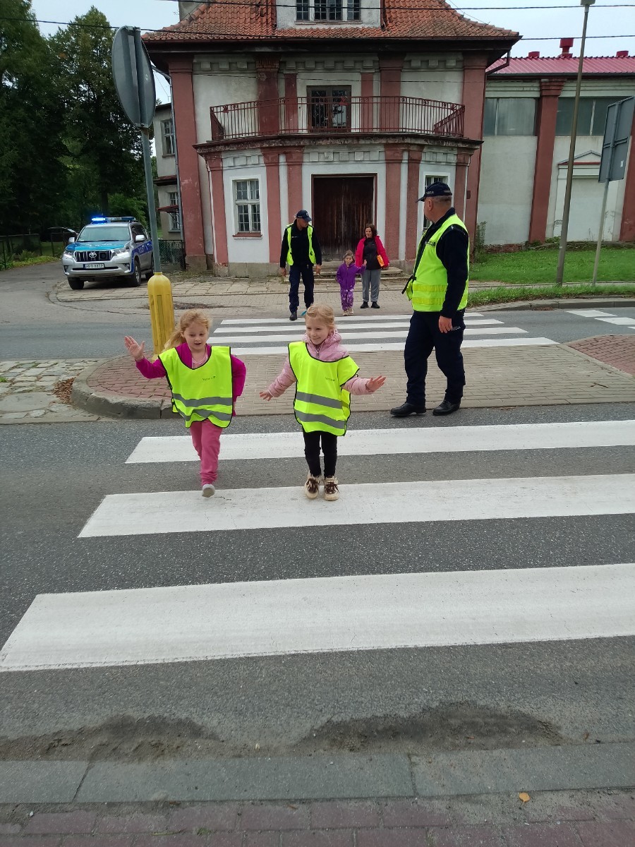 Dzieci z grup starszych Sówki, Leśne skrzaty oraz Biedronki odwiedzili funkcjonariusze policji drogowej , którzy przeprowadzili zajęcia edukacyjne na temat bezpieczeństwa w ruchu ulicznym. Wydarzenie odbyło się w ramach zajęć ,,Moja droga do przedszkola”, której celem jest kształtowanie prawidłowych nawyków i świadomości wśród najmłodszych uczestników ruchu drogowego. Policjanci opowiedzieli przedszkolakom o zasadach bezpiecznego przechodzenia przez jezdnię, znaczeniu znaków drogowych. Dzieci dowiedziały się również, dlaczego ważne jest noszenie odblasków, zwłaszcza jesienią i zimą, gdy wcześniej zapada zmrok.                                
Takie spotkania są bardzo ważne. Dzieci w tym wieku chłoną wiedzę jak gąbka.                  Warto więc już teraz uczyć je zasad, które mogą uratować życie. Przedszkolaki pożegnały policjanta gromkimi brawami i obiecały zawsze pamiętać o zasadach bezpieczeństwa.
Spotkanie z policjantem było nie tylko cenną lekcją, ale też okazją do wzbudzenia w dzieciach zaufania do funkcjonariuszy. To ważny krok w budowaniu poczucia bezpieczeństwa od najmłodszych lat.
