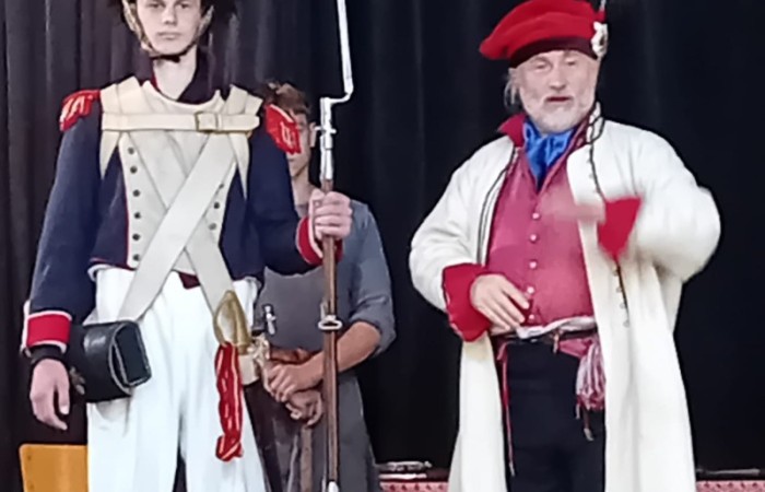 Każdego roku uczniowie naszej szkoły mają niepowtarzalną okazję wziąć udział w wyjątkowym wydarzeniu edukacyjnym - ŻYWEJ LEKCJI HISTORII, prowadzonej przez grupę rekonstrukcyjną Chorągiew Komturstwa Gniewskiego. To spotkanie, które na długo pozostaje w pamięci uczestników, łącząc wiedzę historyczną z emocjami, ruchem i bezpośrednim kontaktem z przeszłością.
W tym roku tematyka spotkań została zrealizowana na dwóch poziomach wiekowych:
Klasy 4-6: Świat starożytnych Greków i Rzymian
Uczniowie klas młodszych przenieśli się do czasów starożytności - epoki potężnych cywilizacji, mitologii, igrzysk olimpijskich i legionów rzymskich. Dzięki strojom z epoki, realistycznym rekwizytom i barwnym opowieściom rekonstruktorów, dzieci mogły poczuć atmosferę antycznego świata. Dowiedzieli się, jak wyglądało życie codzienne Greków i Rzymian, jakie były zwyczaje wojenne, a nawet jak wyglądały ćwiczenia wojskowe legionistów. Zajęcia - prowadzone w formie interaktywnej - dały uczniom możliwość przymierzenia elementów uzbrojenia oraz wzięcia udziału w krótkich pokazach.
Klasy 7-8: Długi wiek XIX
Starsze klasy uczestniczyły w lekcji poświęconej Długiemu wiekowi XIX, czyli okresowi, który ukształtował współczesny świat. Rekonstruktorzy przybliżyli wydarzenia związane z rewolucjami, walką o niepodległość, przemianami społecznymi i narodzinami nowoczesnych idei. Szczególną uwagę poświęcono wydarzeniom ważnym dla Polski - rozbiorom, powstaniom narodowym i postaciom kluczowym dla naszej historii. Uczniowie mogli zobaczyć repliki broni, a także stroje z XIX wieku. Dla wielu była to okazja do poznania historii w sposób bardziej angażujący niż podręcznik - przez opowieści, prezentacje multimedialne i inscenizacje.
Żywa lekcja historii to nie tylko atrakcja, ale przede wszystkim cenna forma nauki. Bezpośredni kontakt z pasjonatami historii oraz aktywne uczestnictwo w przedsięwzięciu sprawia, że uczniowie lepiej zapamiętują materiał, rozbudzają swoją ciekawość i rozwijają szacunek do dziedzictwa kulturowego.