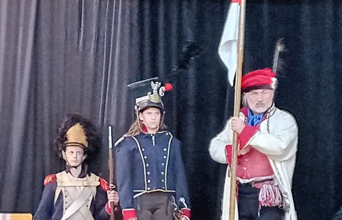 Każdego roku uczniowie naszej szkoły mają niepowtarzalną okazję wziąć udział w wyjątkowym wydarzeniu edukacyjnym - ŻYWEJ LEKCJI HISTORII, prowadzonej przez grupę rekonstrukcyjną Chorągiew Komturstwa Gniewskiego. To spotkanie, które na długo pozostaje w pamięci uczestników, łącząc wiedzę historyczną z emocjami, ruchem i bezpośrednim kontaktem z przeszłością.
W tym roku tematyka spotkań została zrealizowana na dwóch poziomach wiekowych:
Klasy 4-6: Świat starożytnych Greków i Rzymian
Uczniowie klas młodszych przenieśli się do czasów starożytności - epoki potężnych cywilizacji, mitologii, igrzysk olimpijskich i legionów rzymskich. Dzięki strojom z epoki, realistycznym rekwizytom i barwnym opowieściom rekonstruktorów, dzieci mogły poczuć atmosferę antycznego świata. Dowiedzieli się, jak wyglądało życie codzienne Greków i Rzymian, jakie były zwyczaje wojenne, a nawet jak wyglądały ćwiczenia wojskowe legionistów. Zajęcia - prowadzone w formie interaktywnej - dały uczniom możliwość przymierzenia elementów uzbrojenia oraz wzięcia udziału w krótkich pokazach.
Klasy 7-8: Długi wiek XIX
Starsze klasy uczestniczyły w lekcji poświęconej Długiemu wiekowi XIX, czyli okresowi, który ukształtował współczesny świat. Rekonstruktorzy przybliżyli wydarzenia związane z rewolucjami, walką o niepodległość, przemianami społecznymi i narodzinami nowoczesnych idei. Szczególną uwagę poświęcono wydarzeniom ważnym dla Polski - rozbiorom, powstaniom narodowym i postaciom kluczowym dla naszej historii. Uczniowie mogli zobaczyć repliki broni, a także stroje z XIX wieku. Dla wielu była to okazja do poznania historii w sposób bardziej angażujący niż podręcznik - przez opowieści, prezentacje multimedialne i inscenizacje.
Żywa lekcja historii to nie tylko atrakcja, ale przede wszystkim cenna forma nauki. Bezpośredni kontakt z pasjonatami historii oraz aktywne uczestnictwo w przedsięwzięciu sprawia, że uczniowie lepiej zapamiętują materiał, rozbudzają swoją ciekawość i rozwijają szacunek do dziedzictwa kulturowego.