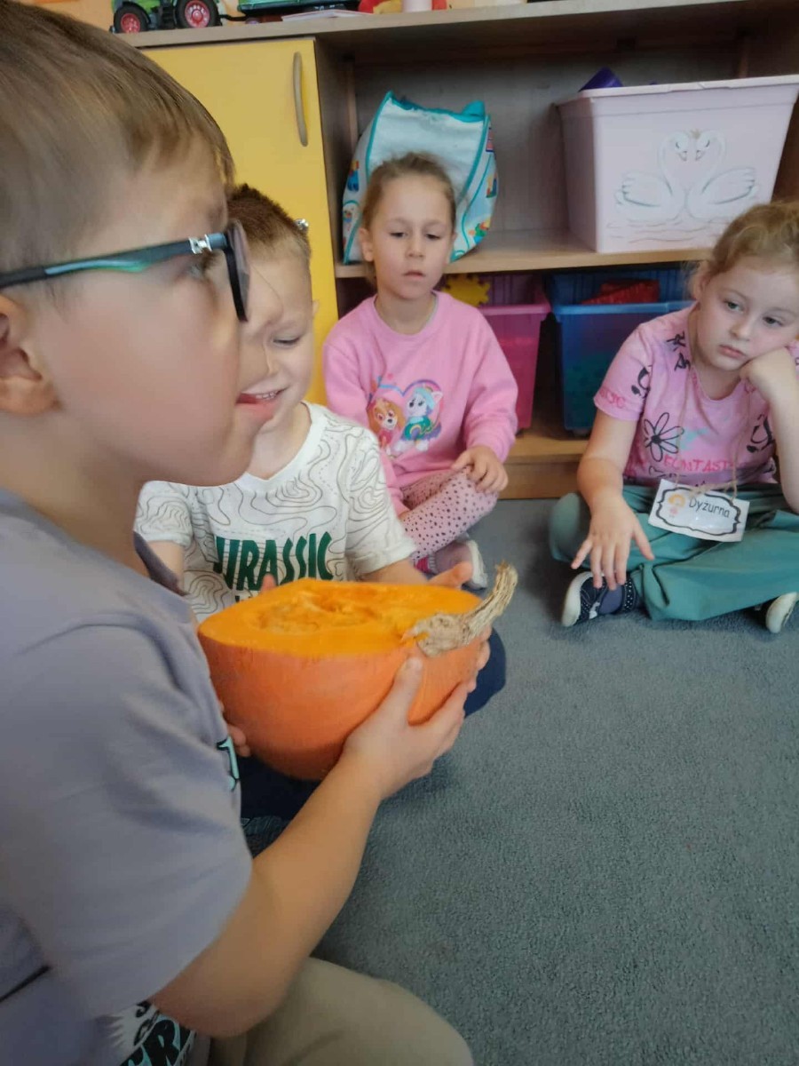 31 października nasze przedszkole zamieniło się w prawdziwą dyniową krainę! W salach królował kolor pomarańczowy, a wszędzie można było zobaczyć uśmiechnięte buzie dzieci i  dynie w różnych kształtach i rozmiarach.Przedszkolaki chętnie brały udział w zabawach muzyczno-ruchowych oraz zajęciach plastycznych z dynią w roli głównej.
Dzieci dowiedziały się, że dynia to nie tylko piękna ozdoba jesieni, ale również zdrowe i smaczne warzywo, z którego można przygotować wiele pysznych potraw.Na zakończenie dnia dzieci otrzymały dyniowe medale oraz pamiątkowe dyplomy,świadczące o ich udziale i zaangażowaniu w obchody tego święta.
To był dzień pełen radości, kolorów ,niezapomnianych wrażeń i jesiennej magii.
