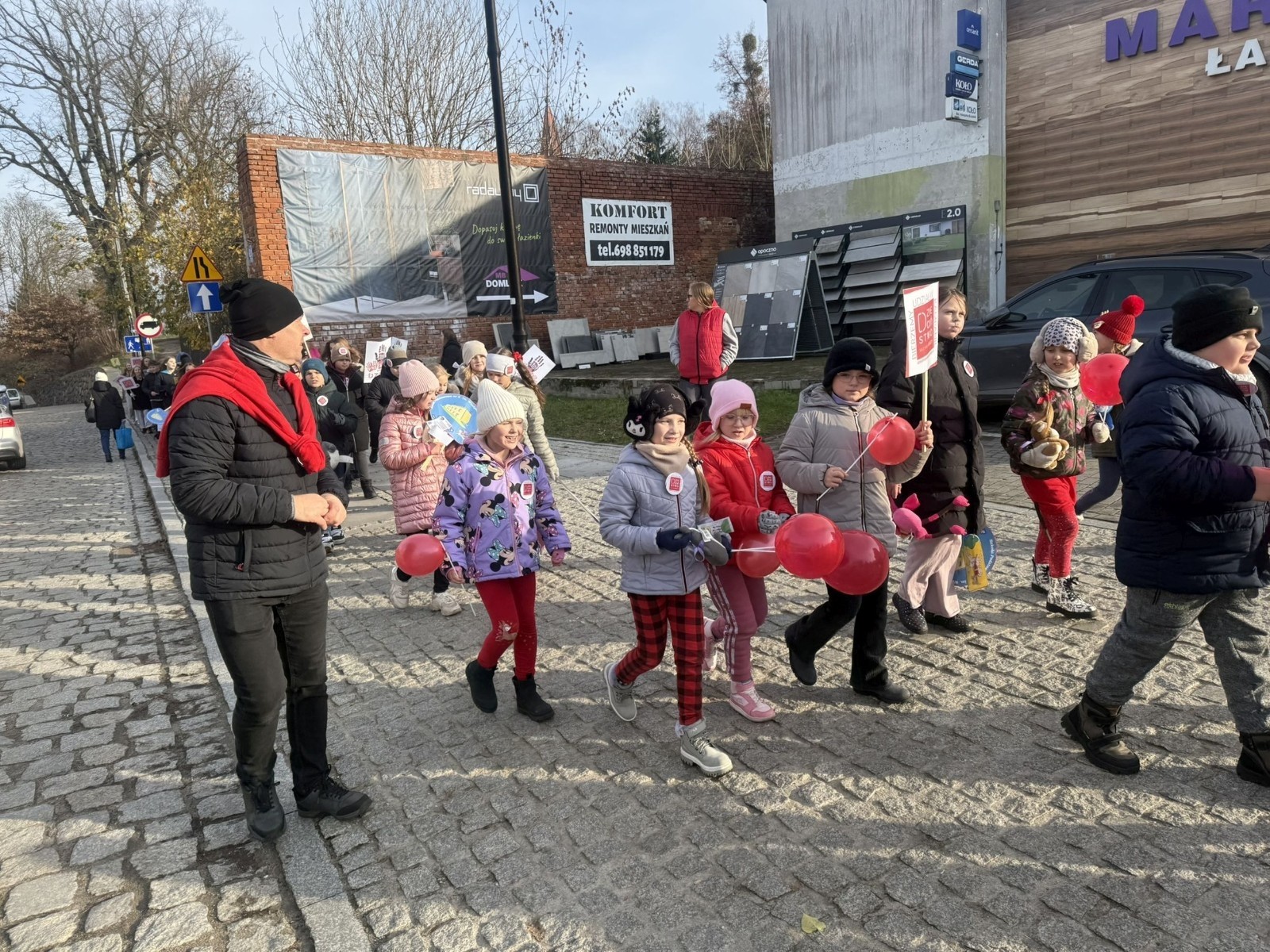 W środę 17.11.2025 nasza szkoła zorganizowała wyjątkowe wydarzenie, które było zaczątkiem podsumowania kampanii „Dzieciństwo bez Przemocy”. Dzień rozpoczął się od radosnego marszu, w którym dzieci grup przedszkolnych z wychowawczyniami oraz uczniowie wraz z nauczycielami przeszli ulicami naszego miasta. Podczas tego wydarzenia dzieci rozdawały mieszkańcom kolorowe maskotki, promując ideę bezpiecznego i szczęśliwego dzieciństwa.
Ważnym punktem dnia było spotkanie w Urzędzie Miasta z panią burmistrz, która serdecznie przyjęła naszych reprezentantów. Rozmowy dotyczyły dalszych działań na rzecz dzieci oraz wspierania inicjatyw mających na celu eliminację przemocy wśród najmłodszych.