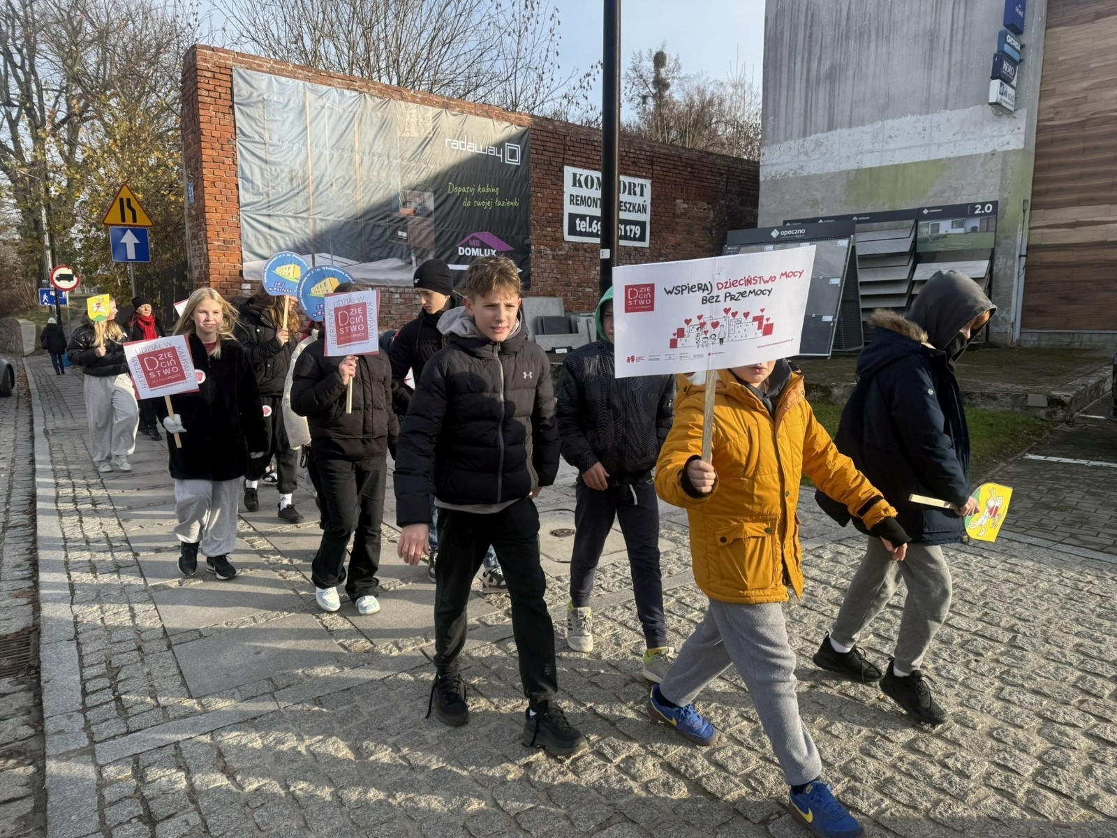 W środę 17.11.2025 nasza szkoła zorganizowała wyjątkowe wydarzenie, które było zaczątkiem podsumowania kampanii „Dzieciństwo bez Przemocy”. Dzień rozpoczął się od radosnego marszu, w którym dzieci grup przedszkolnych z wychowawczyniami oraz uczniowie wraz z nauczycielami przeszli ulicami naszego miasta. Podczas tego wydarzenia dzieci rozdawały mieszkańcom kolorowe maskotki, promując ideę bezpiecznego i szczęśliwego dzieciństwa.
Ważnym punktem dnia było spotkanie w Urzędzie Miasta z panią burmistrz, która serdecznie przyjęła naszych reprezentantów. Rozmowy dotyczyły dalszych działań na rzecz dzieci oraz wspierania inicjatyw mających na celu eliminację przemocy wśród najmłodszych.