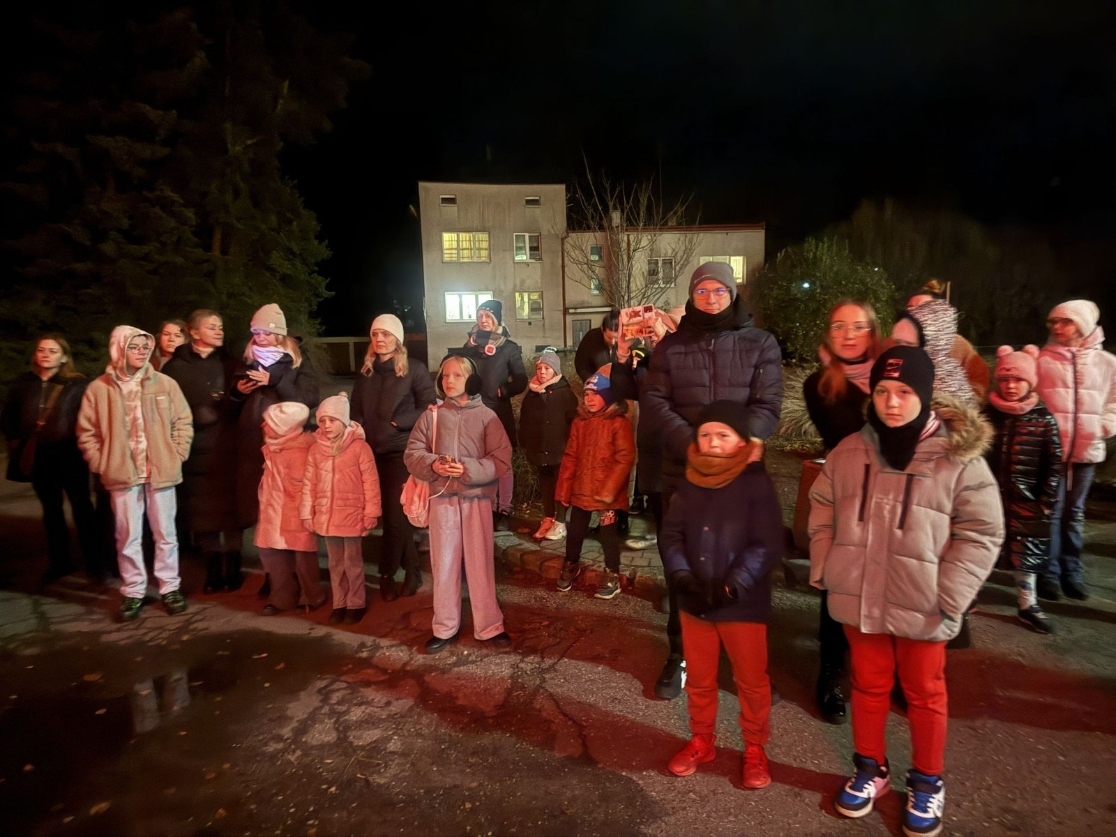 O godzinie 17:00 pod szkołą rozpoczęła się impreza, która zgromadziła około 200 osób. Szkoła została podświetlona na czerwono, co symbolizowało naszą jedność w walce z przemocą. Był to akcent podsumowujący nasze wcześ iej sze  działania w ramach Kampanii Ogólnopolskiej „Dzieciństwo bez Przemocy”. Od października uczniowie uczestniczyli w lekcjach online przygotowanych przez Fundację Dajemy Dzieciom Siłę. Rodzice również zostali objęci wsparciem w postaci webinaru online ww. fudacji.
Uczestnicy mogli wziąć udział w wspólnym śpiewaniu, quizie wiedzy o przemocy oraz tworzeniu „kamieni mocy” – symboli pozytywnej energii i wsparcia. Dodatkowo, w ramach konkursów, przyznano nagrody ufundowane przez Urząd Miejski w Pasłęku.
Ten cudowny czas umilił nam smaczny poczęstunek, w tym grochówka, pizza i ciasta, gorąca kawa i herbatka przygotowany przez panie kucharki i rodziców.
W wydarzeniu uczestniczyli również zaproszeni goście, w tym Burmistrz Pasłęka – pani Elżbieta Wasiuk,  podinspektor KP Pasłęk – pani Agnieszka Bielewicz - Piechowiak oraz przedstawiciel Kuratorium Oświaty w Elblągu – pani Teresa Bednarz, którzy wspierają nasze działania. Ich obecność była dowodem na to, jak ważna jest współpraca lokalnej społeczności w walce z przemocą wobec dzieci. Dziękujemy wszystkim, którzy wzięli udział w tym wyjątkowym dniu oraz przyczynili się do jego organizacji. Razem możemy stworzyć bezpieczne i przyjazne środowisko dla naszych dzieci!
