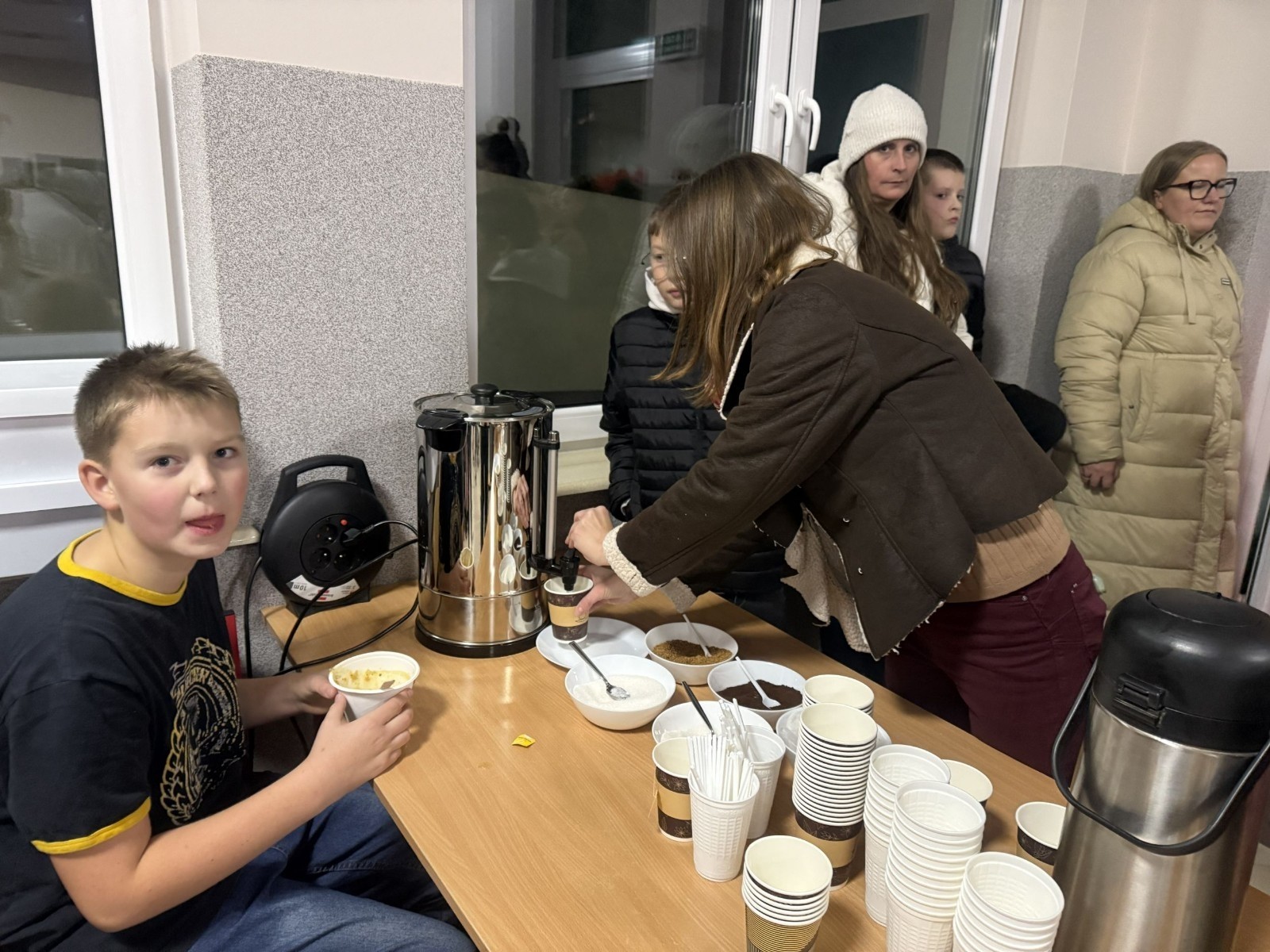 O godzinie 17:00 pod szkołą rozpoczęła się impreza, która zgromadziła około 200 osób. Szkoła została podświetlona na czerwono, co symbolizowało naszą jedność w walce z przemocą. Był to akcent podsumowujący nasze wcześ iej sze  działania w ramach Kampanii Ogólnopolskiej „Dzieciństwo bez Przemocy”. Od października uczniowie uczestniczyli w lekcjach online przygotowanych przez Fundację Dajemy Dzieciom Siłę. Rodzice również zostali objęci wsparciem w postaci webinaru online ww. fudacji.
Uczestnicy mogli wziąć udział w wspólnym śpiewaniu, quizie wiedzy o przemocy oraz tworzeniu „kamieni mocy” – symboli pozytywnej energii i wsparcia. Dodatkowo, w ramach konkursów, przyznano nagrody ufundowane przez Urząd Miejski w Pasłęku.
Ten cudowny czas umilił nam smaczny poczęstunek, w tym grochówka, pizza i ciasta, gorąca kawa i herbatka przygotowany przez panie kucharki i rodziców.
W wydarzeniu uczestniczyli również zaproszeni goście, w tym Burmistrz Pasłęka – pani Elżbieta Wasiuk,  podinspektor KP Pasłęk – pani Agnieszka Bielewicz - Piechowiak oraz przedstawiciel Kuratorium Oświaty w Elblągu – pani Teresa Bednarz, którzy wspierają nasze działania. Ich obecność była dowodem na to, jak ważna jest współpraca lokalnej społeczności w walce z przemocą wobec dzieci. Dziękujemy wszystkim, którzy wzięli udział w tym wyjątkowym dniu oraz przyczynili się do jego organizacji. Razem możemy stworzyć bezpieczne i przyjazne środowisko dla naszych dzieci!
