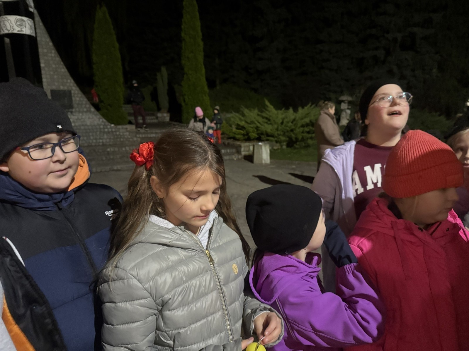 O godzinie 17:00 pod szkołą rozpoczęła się impreza, która zgromadziła około 200 osób. Szkoła została podświetlona na czerwono, co symbolizowało naszą jedność w walce z przemocą. Był to akcent podsumowujący nasze wcześ iej sze  działania w ramach Kampanii Ogólnopolskiej „Dzieciństwo bez Przemocy”. Od października uczniowie uczestniczyli w lekcjach online przygotowanych przez Fundację Dajemy Dzieciom Siłę. Rodzice również zostali objęci wsparciem w postaci webinaru online ww. fudacji.
Uczestnicy mogli wziąć udział w wspólnym śpiewaniu, quizie wiedzy o przemocy oraz tworzeniu „kamieni mocy” – symboli pozytywnej energii i wsparcia. Dodatkowo, w ramach konkursów, przyznano nagrody ufundowane przez Urząd Miejski w Pasłęku.
Ten cudowny czas umilił nam smaczny poczęstunek, w tym grochówka, pizza i ciasta, gorąca kawa i herbatka przygotowany przez panie kucharki i rodziców.
W wydarzeniu uczestniczyli również zaproszeni goście, w tym Burmistrz Pasłęka – pani Elżbieta Wasiuk,  podinspektor KP Pasłęk – pani Agnieszka Bielewicz - Piechowiak oraz przedstawiciel Kuratorium Oświaty w Elblągu – pani Teresa Bednarz, którzy wspierają nasze działania. Ich obecność była dowodem na to, jak ważna jest współpraca lokalnej społeczności w walce z przemocą wobec dzieci. Dziękujemy wszystkim, którzy wzięli udział w tym wyjątkowym dniu oraz przyczynili się do jego organizacji. Razem możemy stworzyć bezpieczne i przyjazne środowisko dla naszych dzieci!
