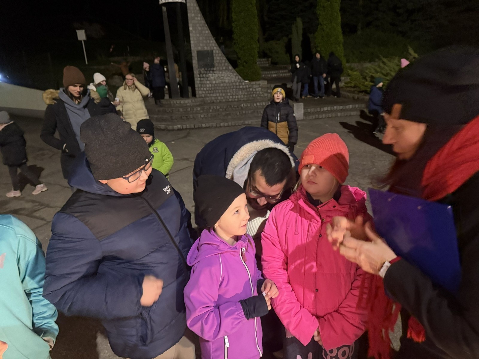 O godzinie 17:00 pod szkołą rozpoczęła się impreza, która zgromadziła około 200 osób. Szkoła została podświetlona na czerwono, co symbolizowało naszą jedność w walce z przemocą. Był to akcent podsumowujący nasze wcześ iej sze  działania w ramach Kampanii Ogólnopolskiej „Dzieciństwo bez Przemocy”. Od października uczniowie uczestniczyli w lekcjach online przygotowanych przez Fundację Dajemy Dzieciom Siłę. Rodzice również zostali objęci wsparciem w postaci webinaru online ww. fudacji.
Uczestnicy mogli wziąć udział w wspólnym śpiewaniu, quizie wiedzy o przemocy oraz tworzeniu „kamieni mocy” – symboli pozytywnej energii i wsparcia. Dodatkowo, w ramach konkursów, przyznano nagrody ufundowane przez Urząd Miejski w Pasłęku.
Ten cudowny czas umilił nam smaczny poczęstunek, w tym grochówka, pizza i ciasta, gorąca kawa i herbatka przygotowany przez panie kucharki i rodziców.
W wydarzeniu uczestniczyli również zaproszeni goście, w tym Burmistrz Pasłęka – pani Elżbieta Wasiuk,  podinspektor KP Pasłęk – pani Agnieszka Bielewicz - Piechowiak oraz przedstawiciel Kuratorium Oświaty w Elblągu – pani Teresa Bednarz, którzy wspierają nasze działania. Ich obecność była dowodem na to, jak ważna jest współpraca lokalnej społeczności w walce z przemocą wobec dzieci. Dziękujemy wszystkim, którzy wzięli udział w tym wyjątkowym dniu oraz przyczynili się do jego organizacji. Razem możemy stworzyć bezpieczne i przyjazne środowisko dla naszych dzieci!
