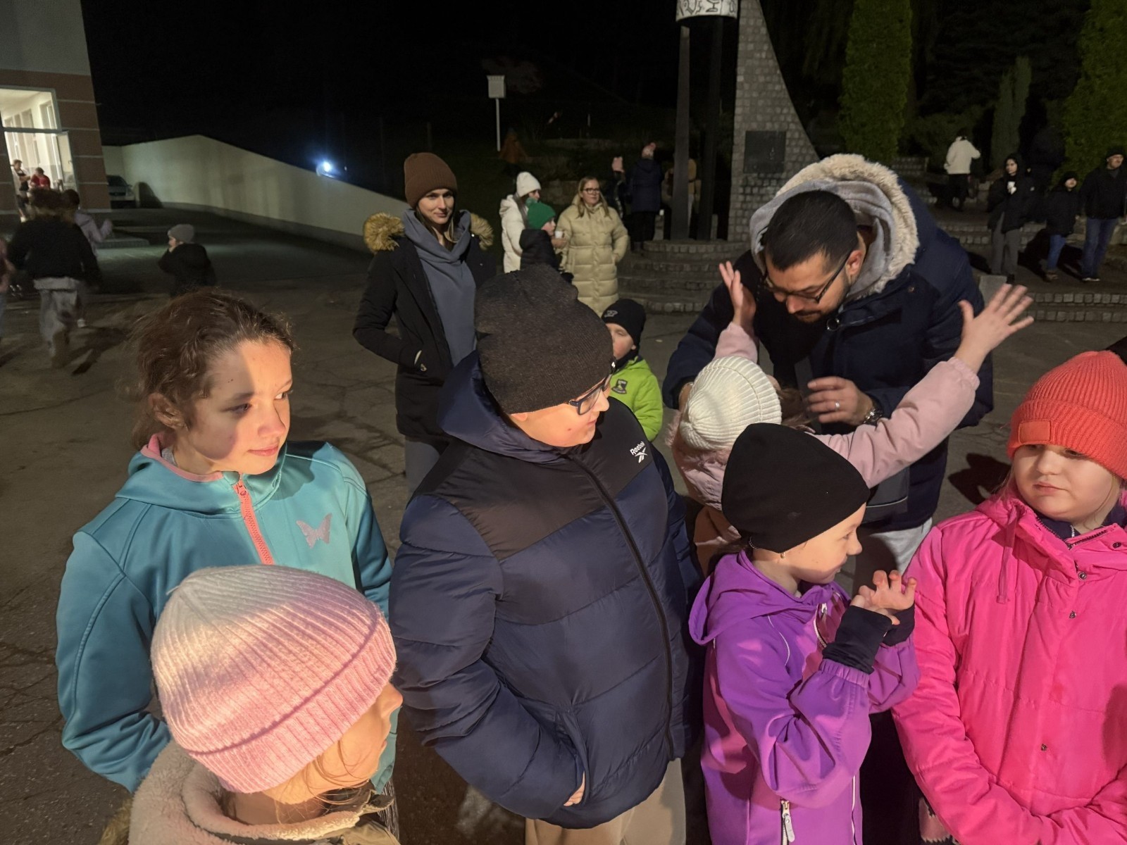 O godzinie 17:00 pod szkołą rozpoczęła się impreza, która zgromadziła około 200 osób. Szkoła została podświetlona na czerwono, co symbolizowało naszą jedność w walce z przemocą. Był to akcent podsumowujący nasze wcześ iej sze  działania w ramach Kampanii Ogólnopolskiej „Dzieciństwo bez Przemocy”. Od października uczniowie uczestniczyli w lekcjach online przygotowanych przez Fundację Dajemy Dzieciom Siłę. Rodzice również zostali objęci wsparciem w postaci webinaru online ww. fudacji.
Uczestnicy mogli wziąć udział w wspólnym śpiewaniu, quizie wiedzy o przemocy oraz tworzeniu „kamieni mocy” – symboli pozytywnej energii i wsparcia. Dodatkowo, w ramach konkursów, przyznano nagrody ufundowane przez Urząd Miejski w Pasłęku.
Ten cudowny czas umilił nam smaczny poczęstunek, w tym grochówka, pizza i ciasta, gorąca kawa i herbatka przygotowany przez panie kucharki i rodziców.
W wydarzeniu uczestniczyli również zaproszeni goście, w tym Burmistrz Pasłęka – pani Elżbieta Wasiuk,  podinspektor KP Pasłęk – pani Agnieszka Bielewicz - Piechowiak oraz przedstawiciel Kuratorium Oświaty w Elblągu – pani Teresa Bednarz, którzy wspierają nasze działania. Ich obecność była dowodem na to, jak ważna jest współpraca lokalnej społeczności w walce z przemocą wobec dzieci. Dziękujemy wszystkim, którzy wzięli udział w tym wyjątkowym dniu oraz przyczynili się do jego organizacji. Razem możemy stworzyć bezpieczne i przyjazne środowisko dla naszych dzieci!
